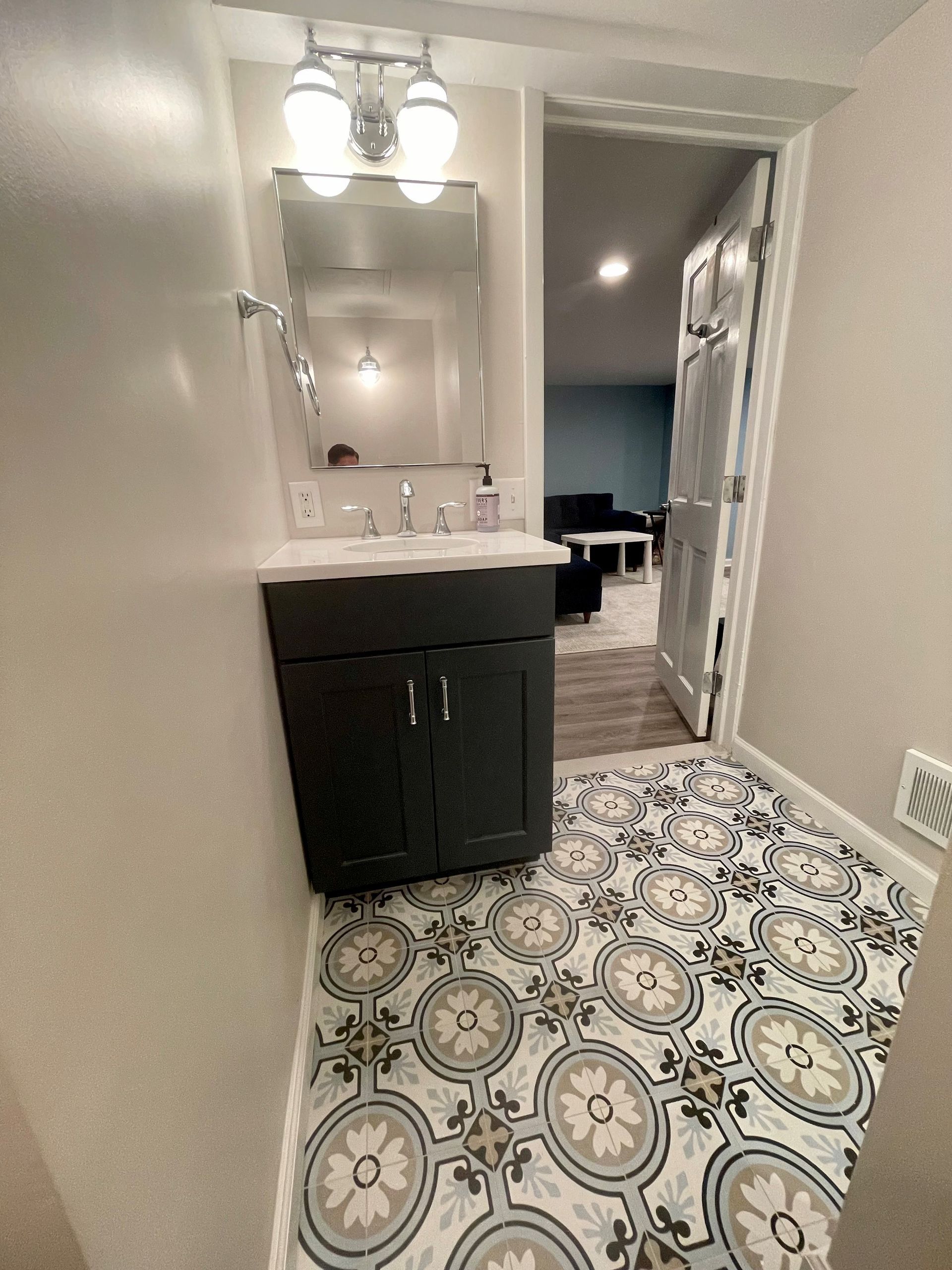A bathroom with a sink, mirror, and tile floor.