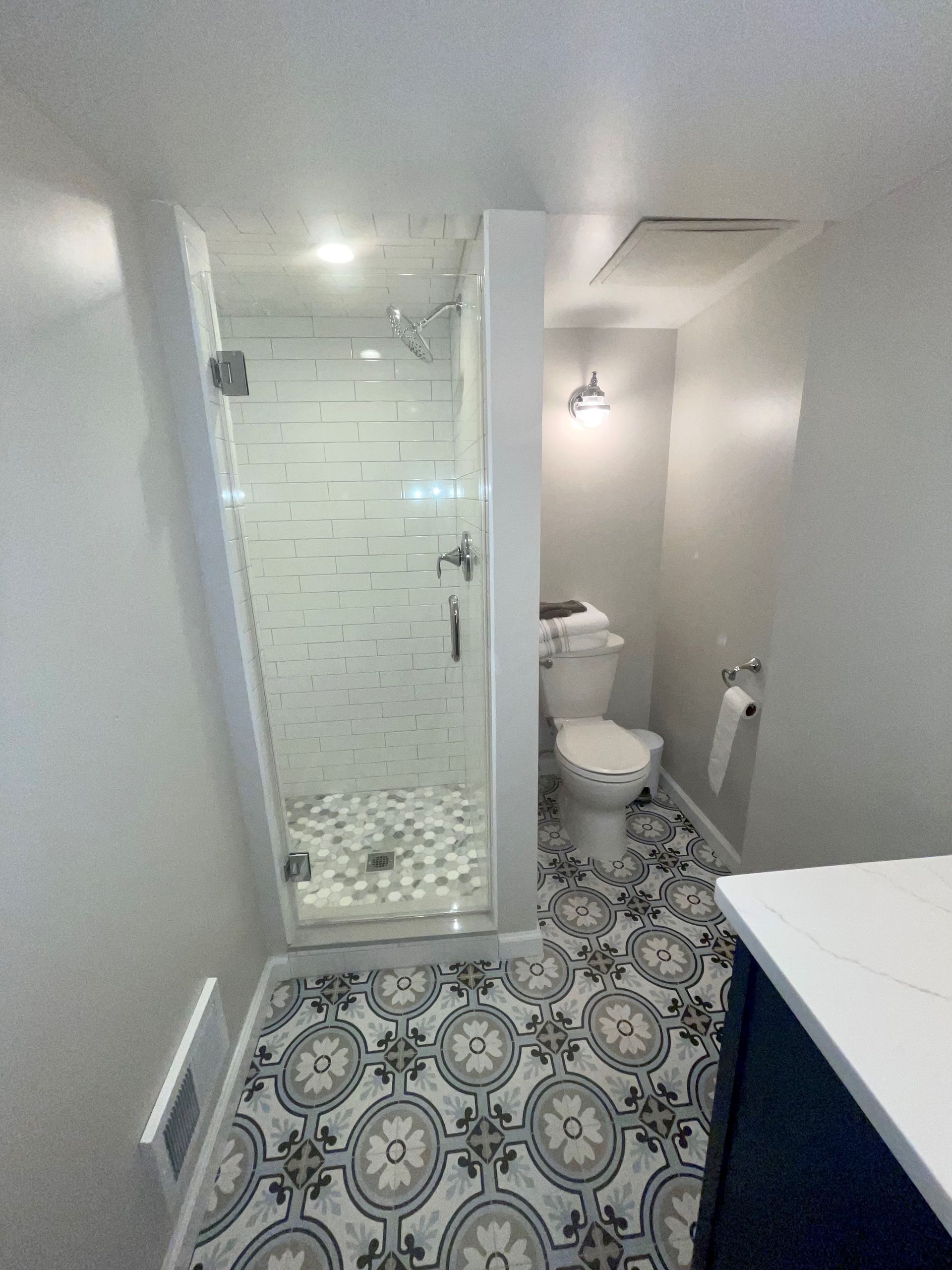 A bathroom with a toilet, shower, and tiled floor.