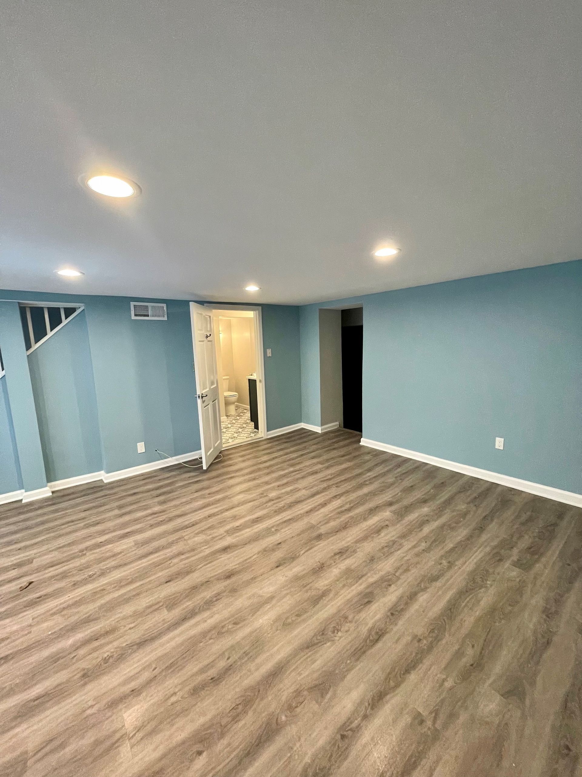 A large empty room with wooden floors and blue walls.