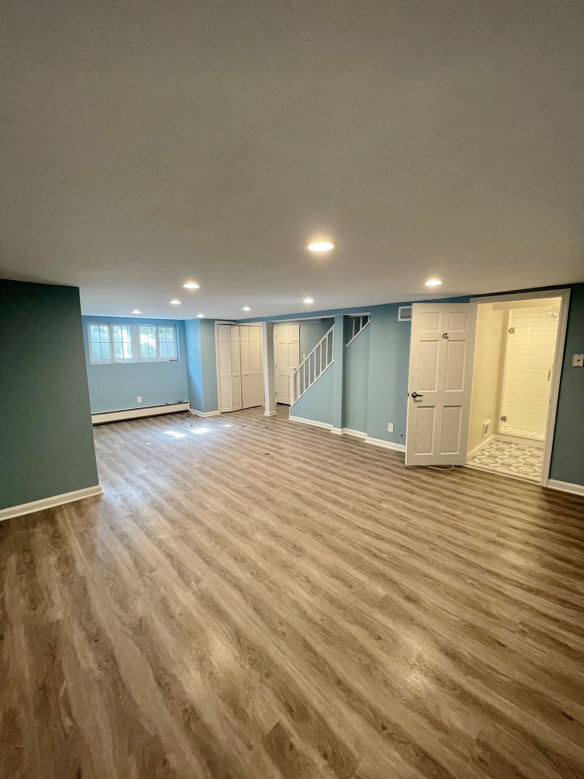 A large empty basement with wooden floors and blue walls.