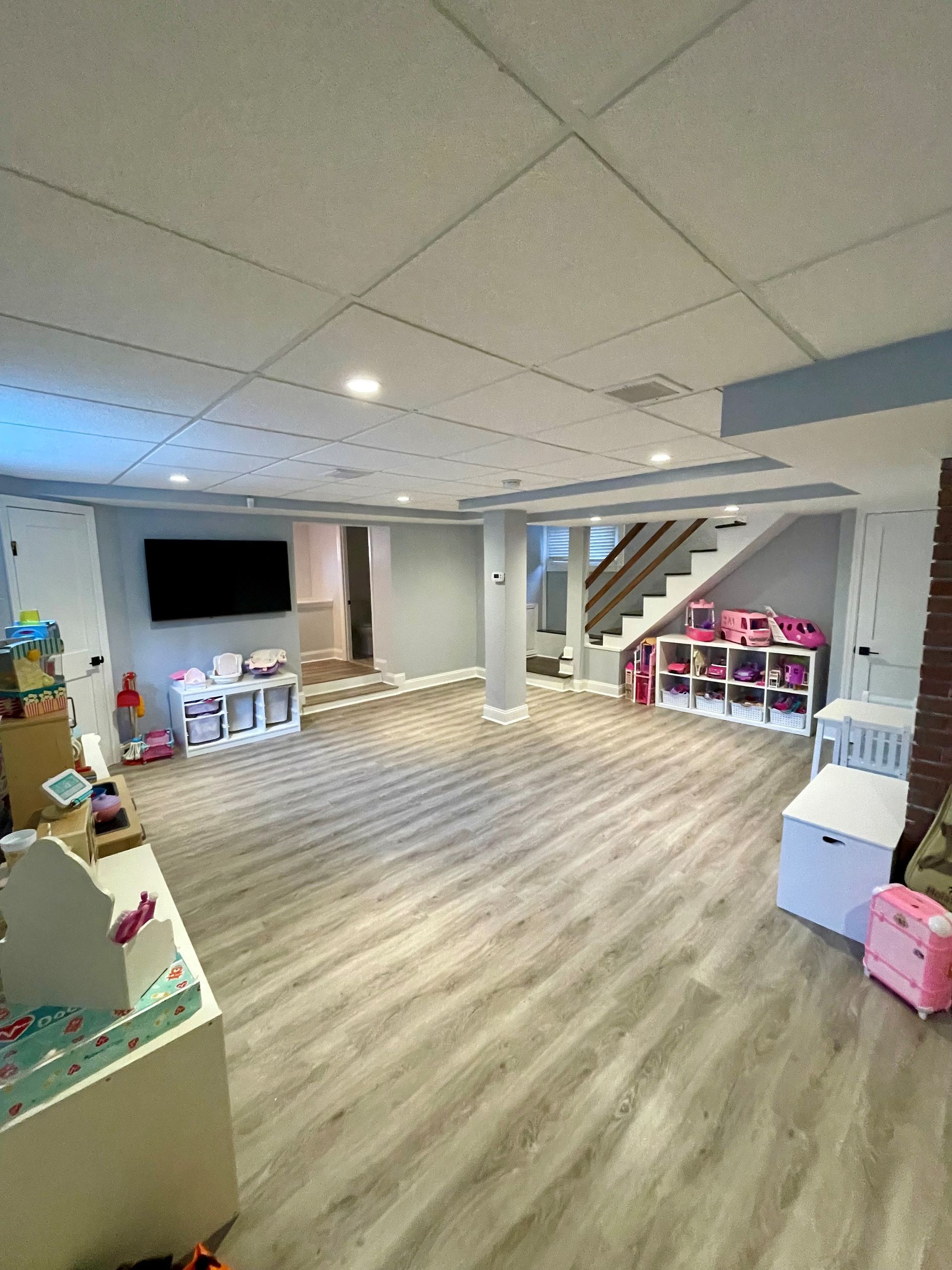 A basement with a lot of toys and a flat screen tv.
