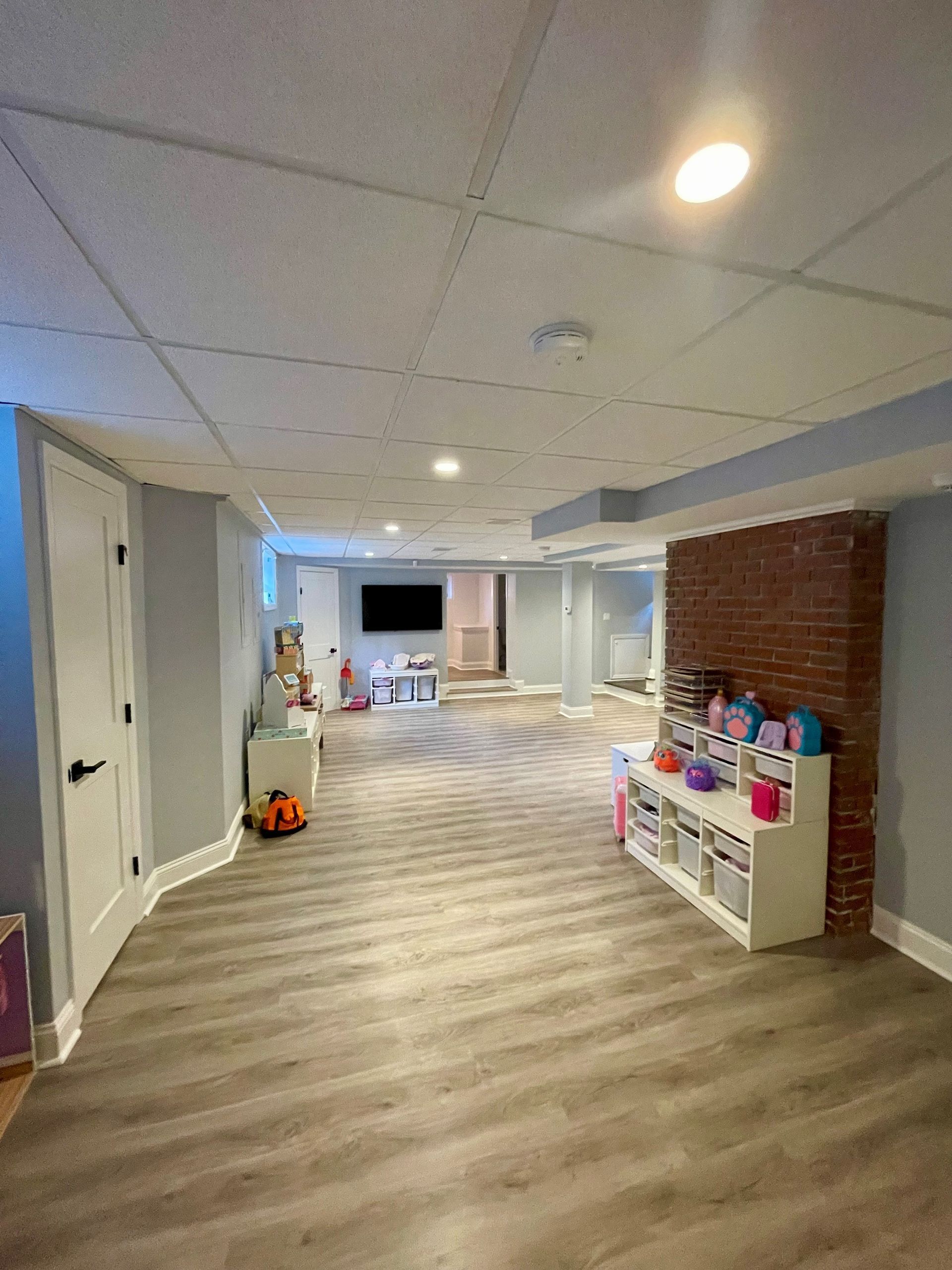 A large basement with hardwood floors and a brick wall.