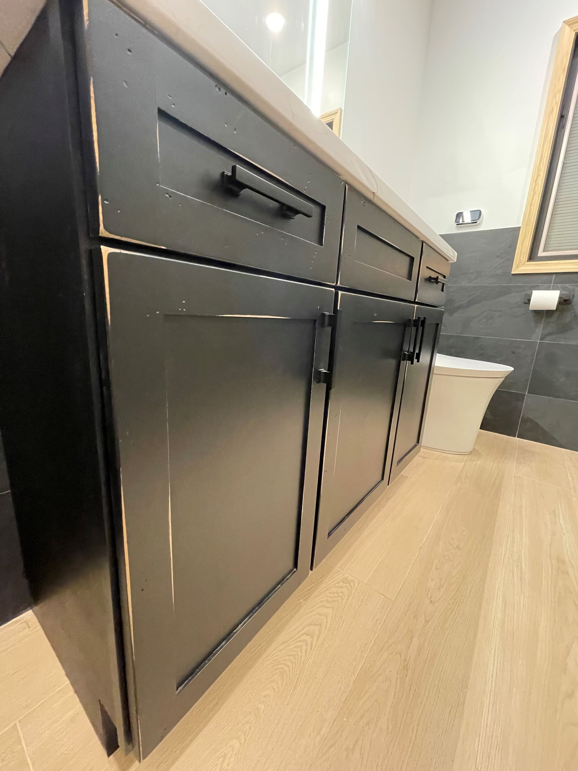 A bathroom with black cabinets and a toilet.