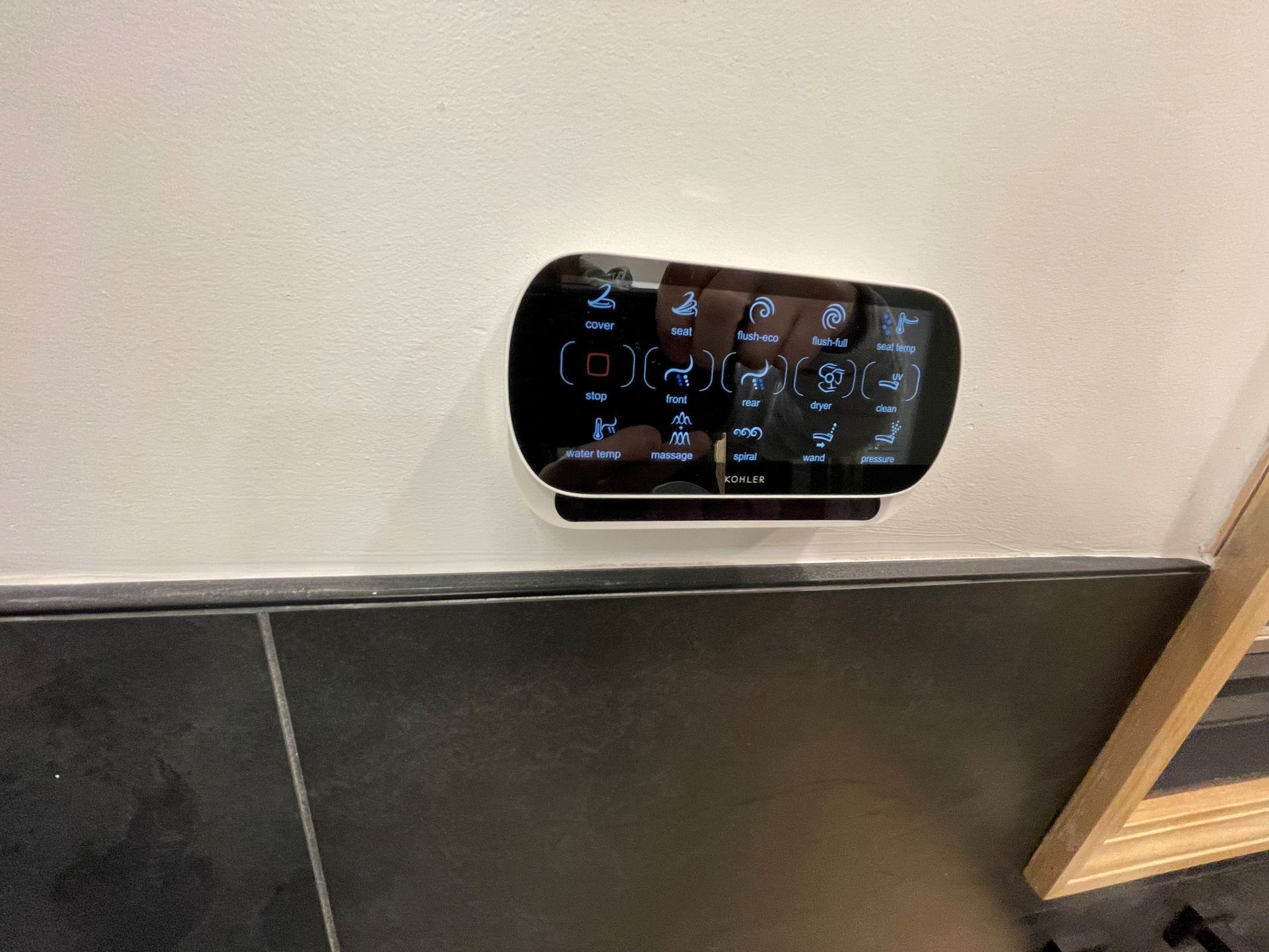 A remote control is mounted on a wall next to a door.