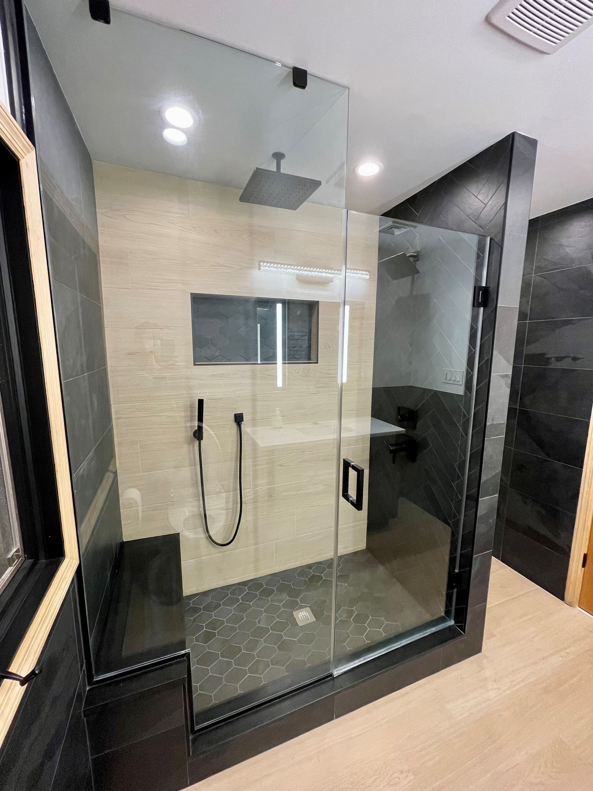 A bathroom with a walk in shower with a glass door.