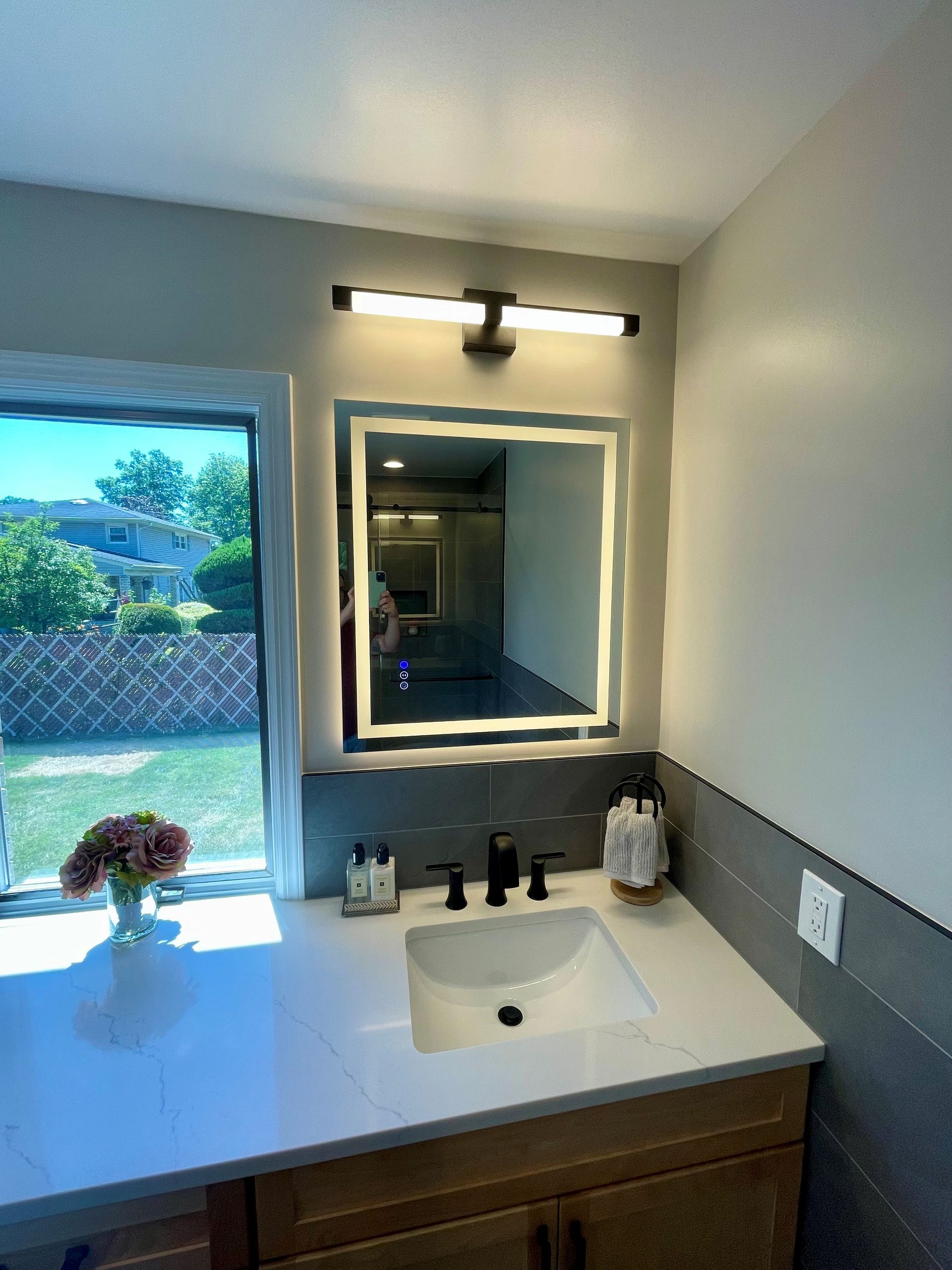 A bathroom with a sink, mirror, and window.