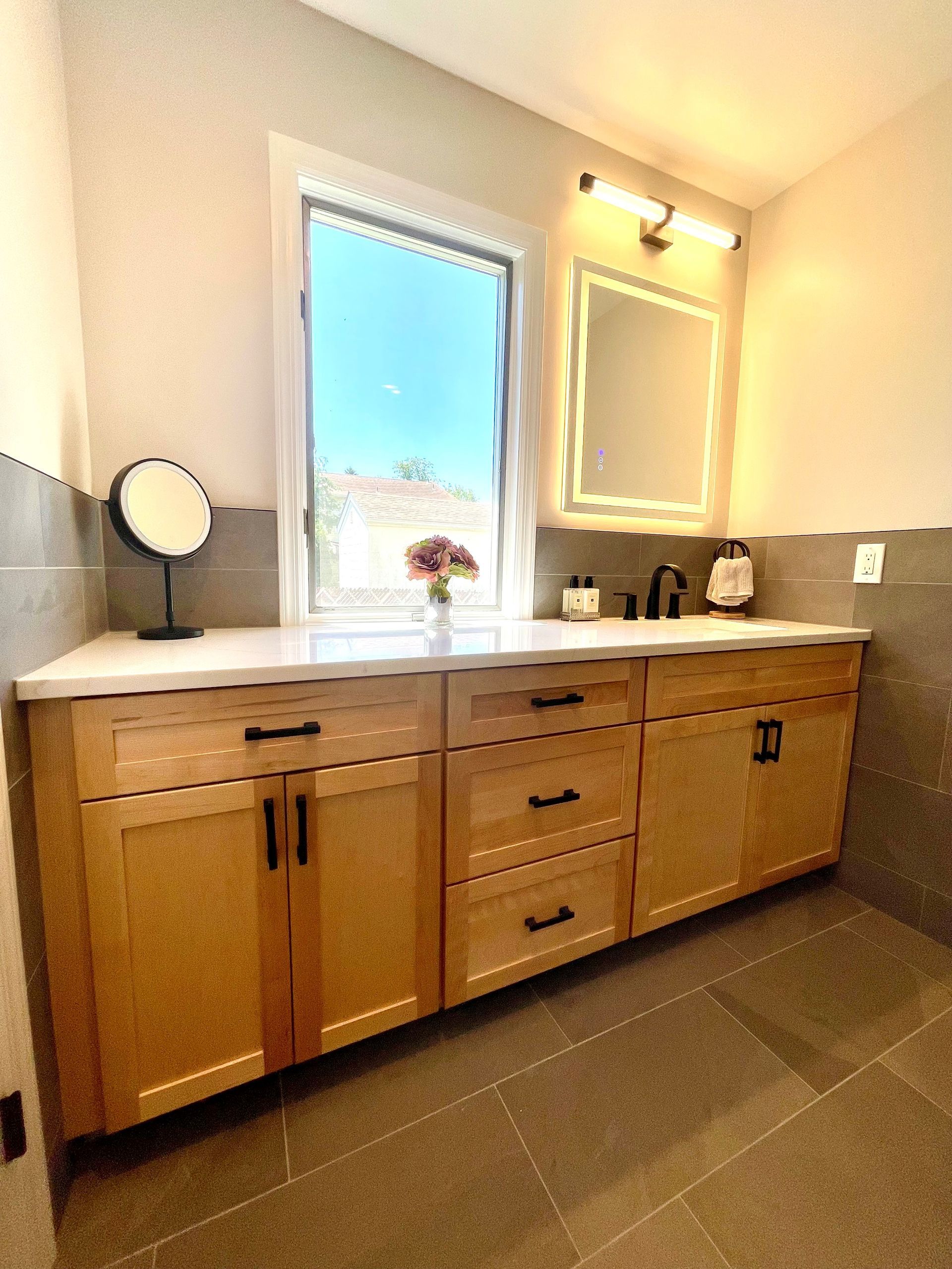 A bathroom with two sinks, a mirror, and a window.