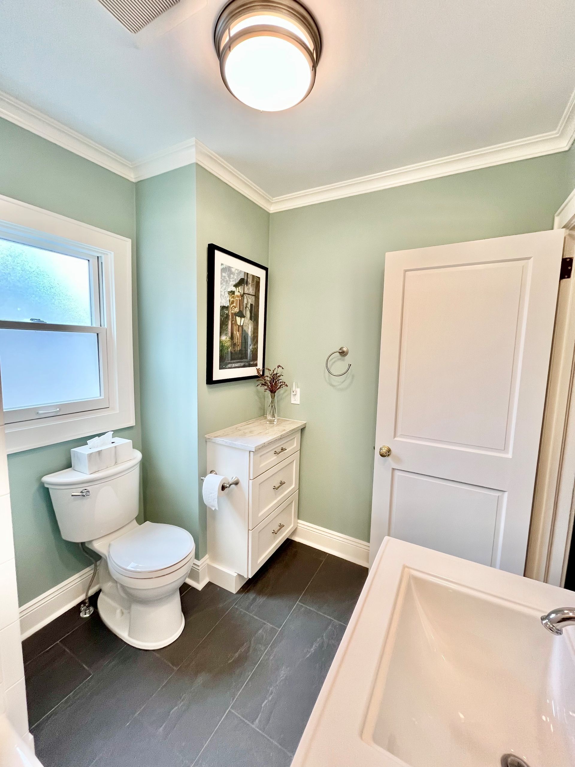 A bathroom with a toilet, sink and window