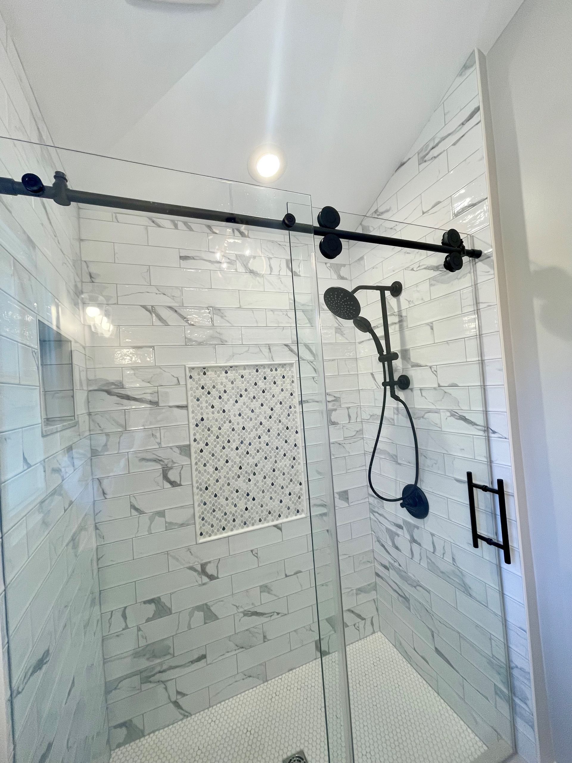 A shower with a sliding glass door and a shower head.