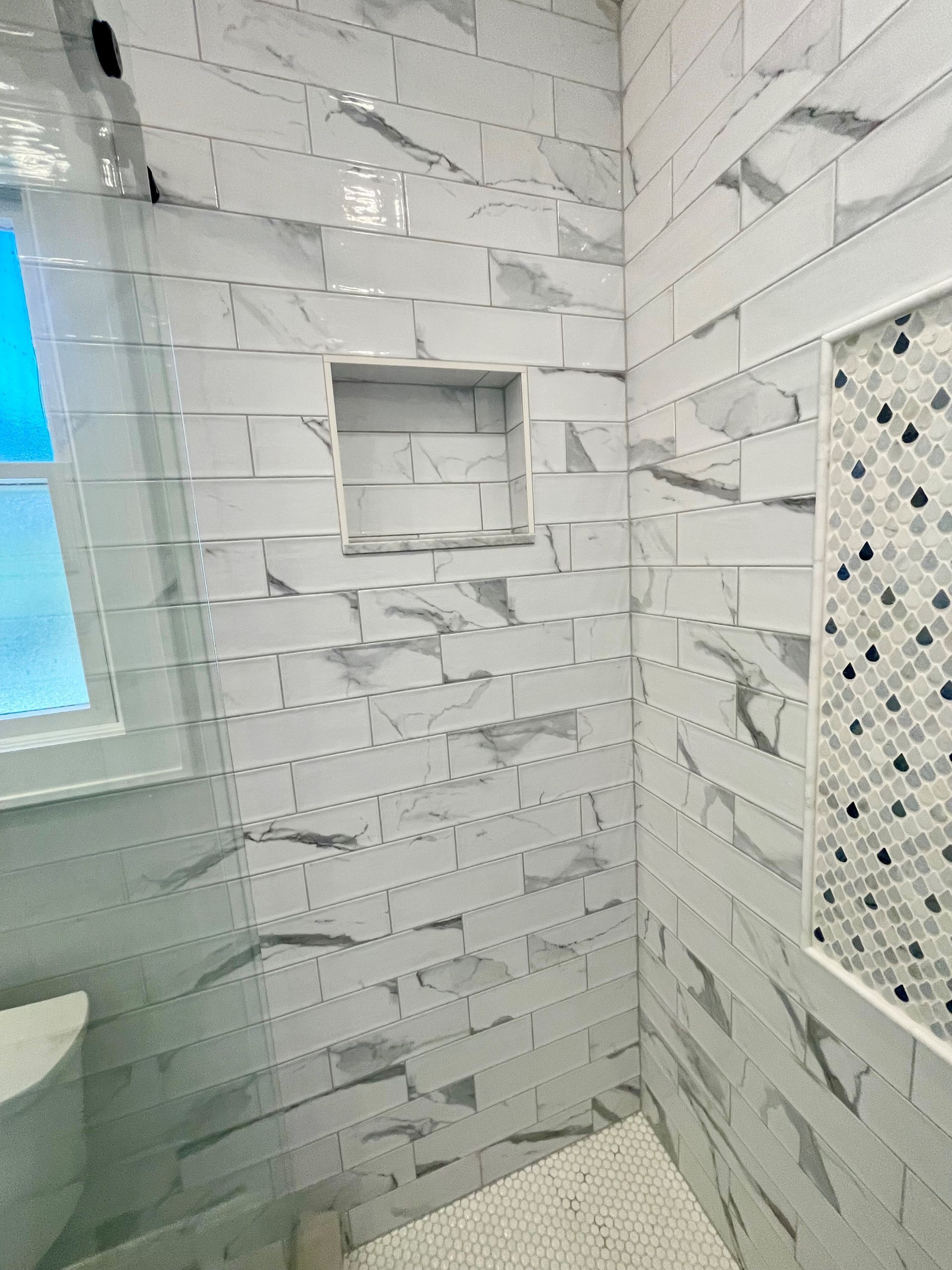 A bathroom with white tiles and a window.