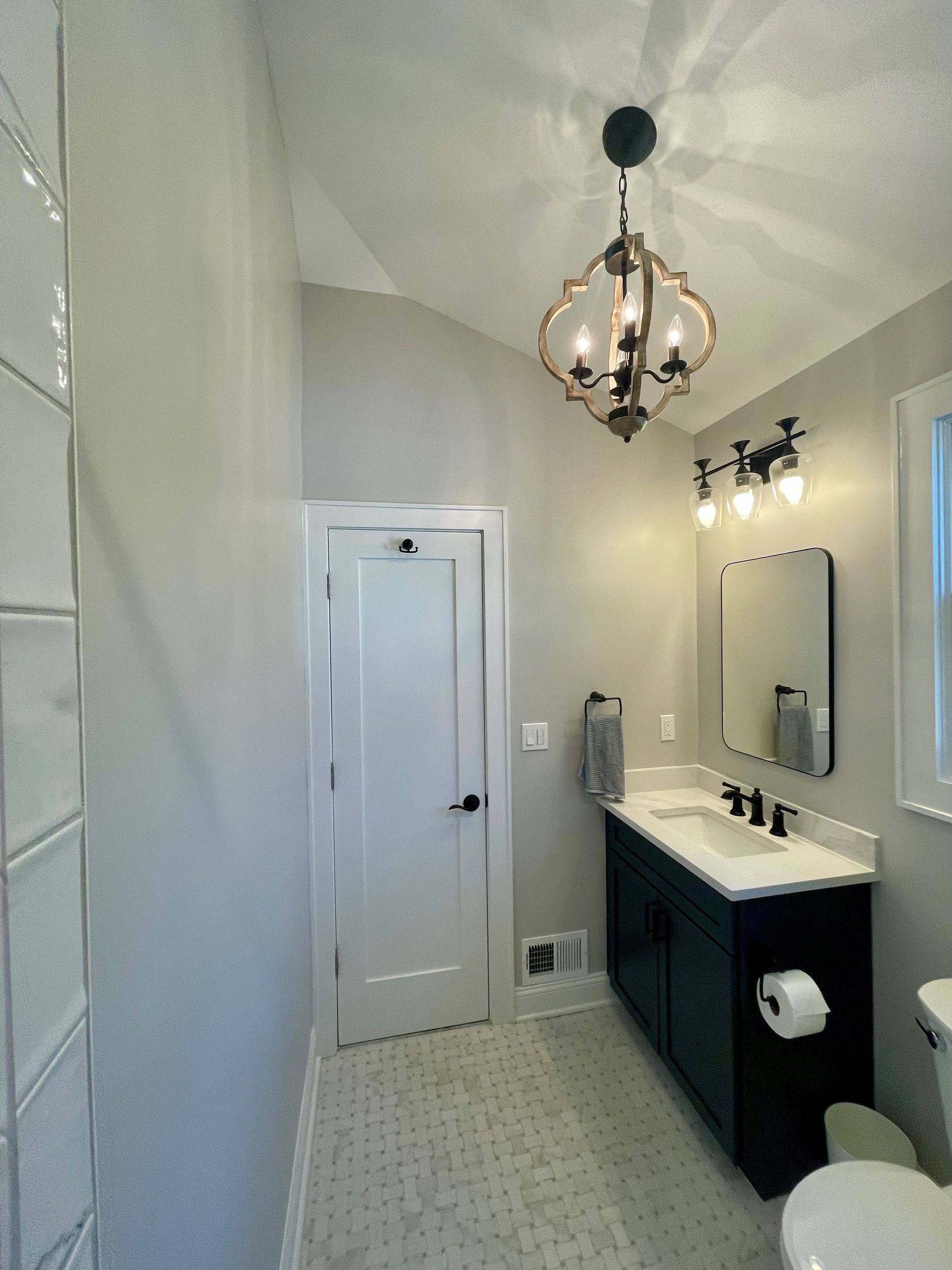 A bathroom with a sink, toilet, mirror and chandelier.