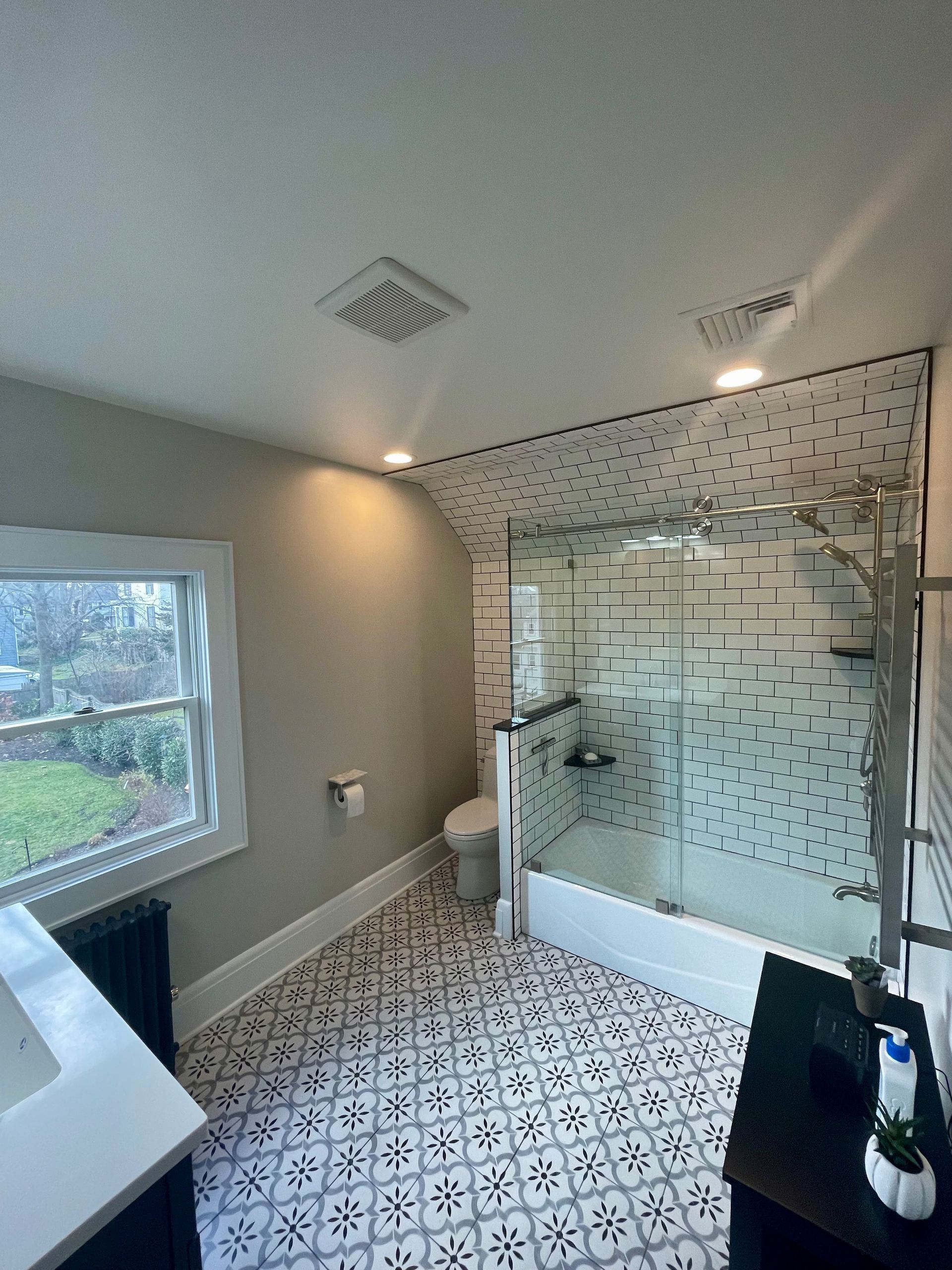 A bathroom with a walk-in shower, toilet, sink and window.