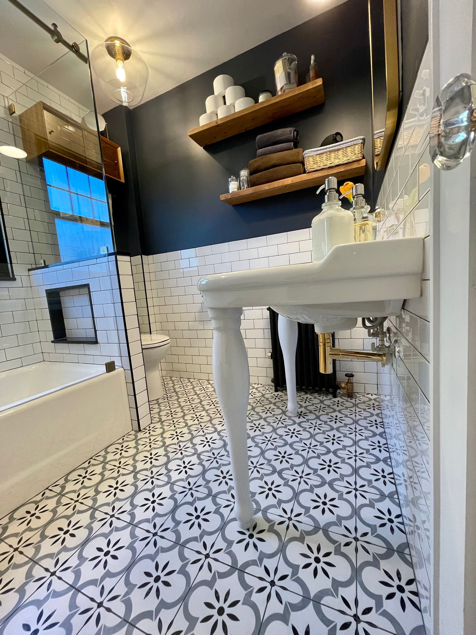 A bathroom with a sink, bathtub, toilet and shelves.