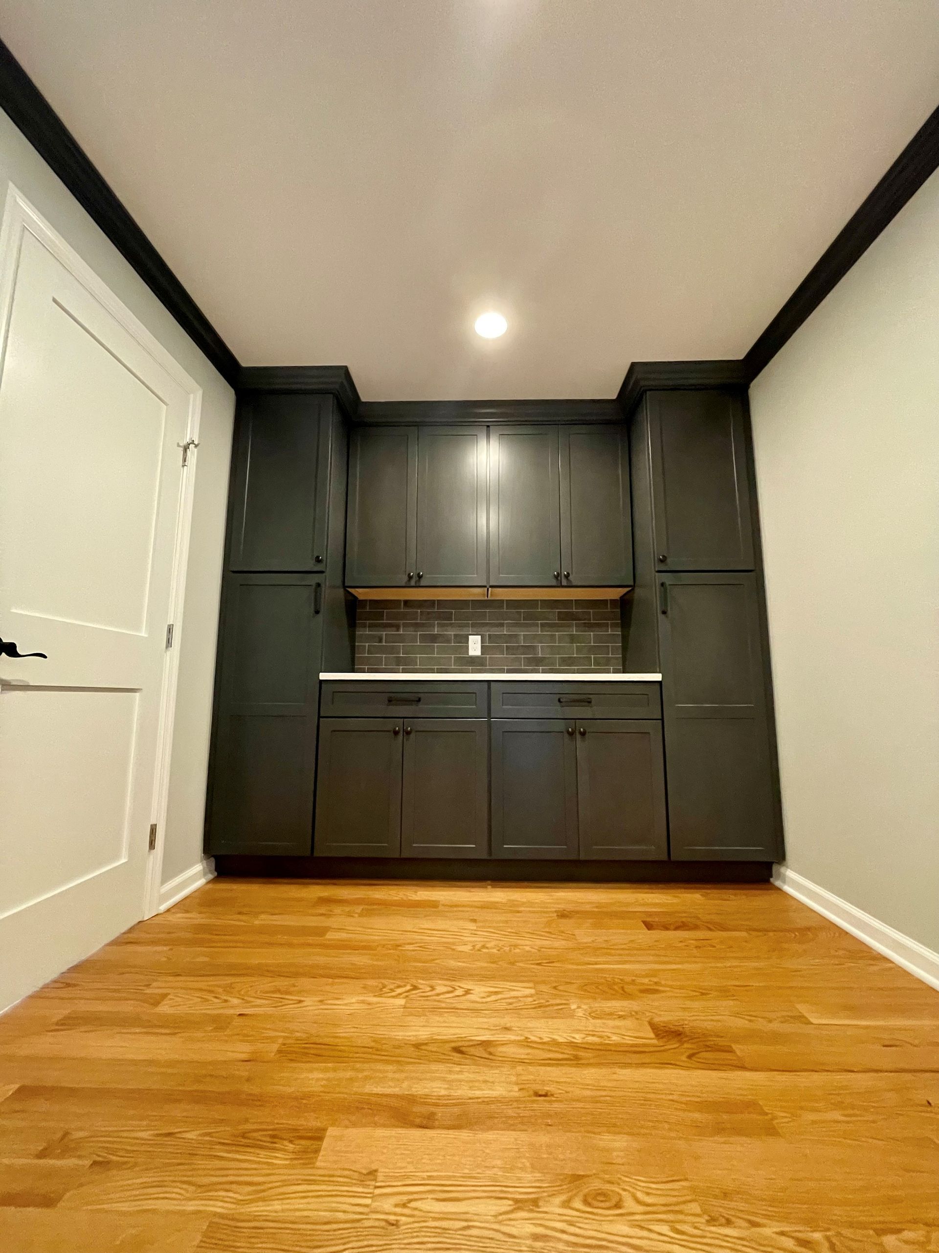 A kitchen with black cabinets and hardwood floors