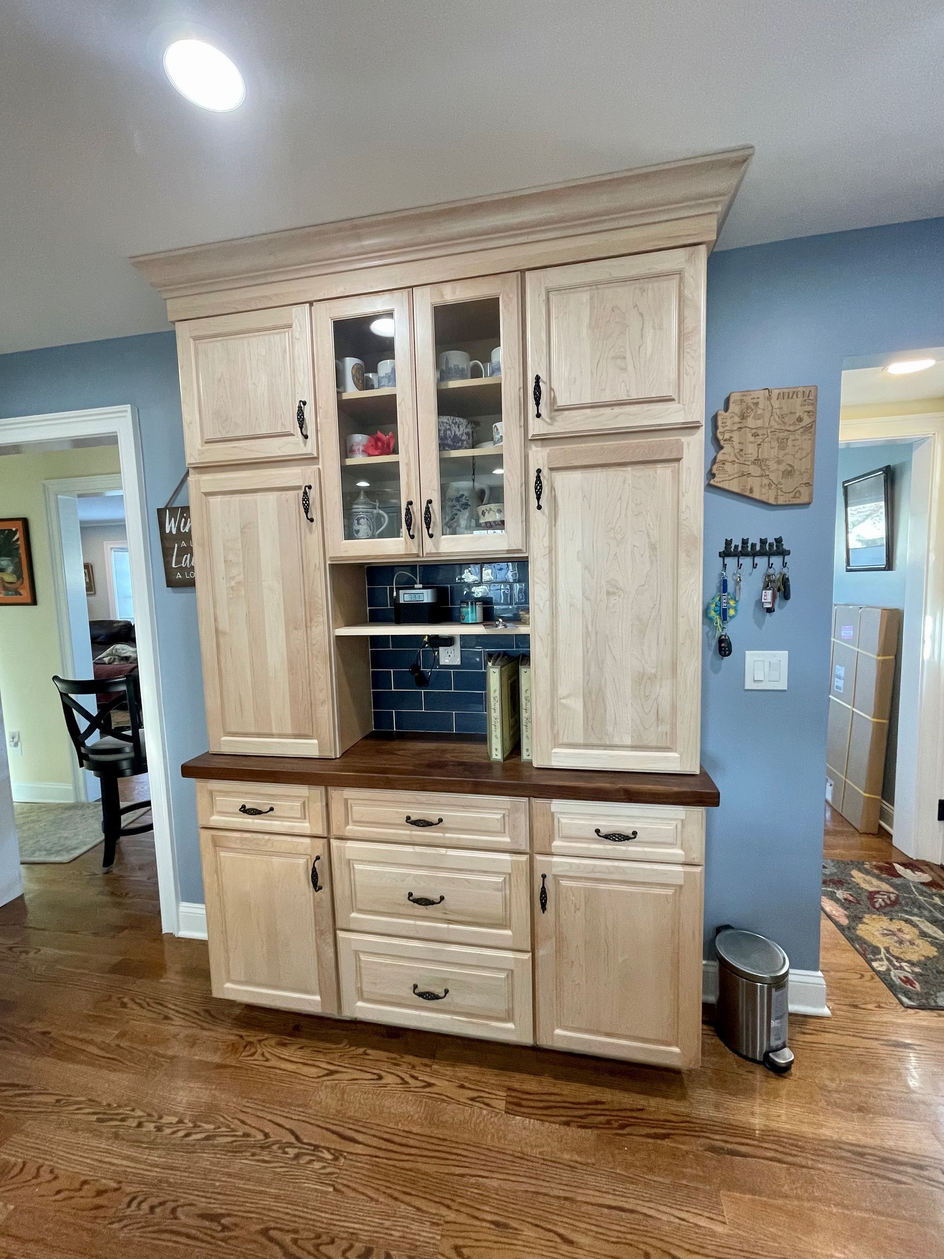 A kitchen with a hutch and a trash can on the floor