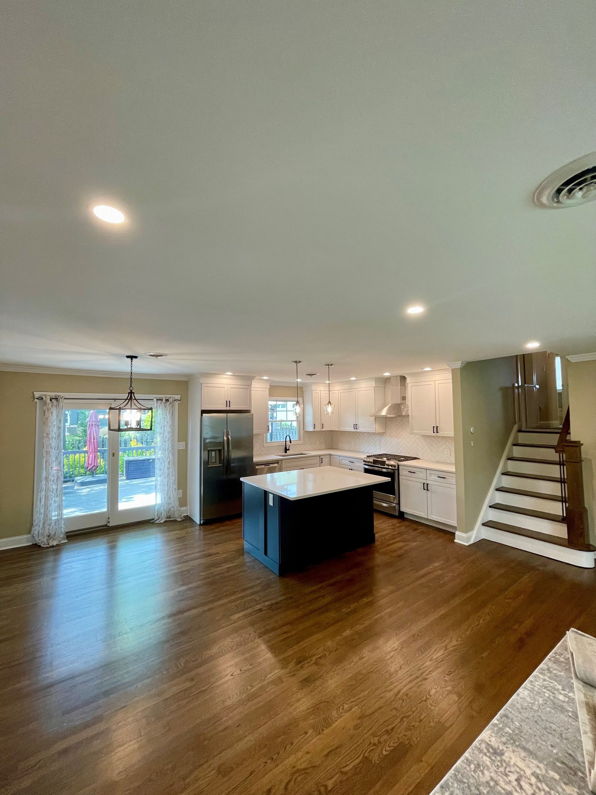 A kitchen with a large island in the middle of it and stairs leading up to it.