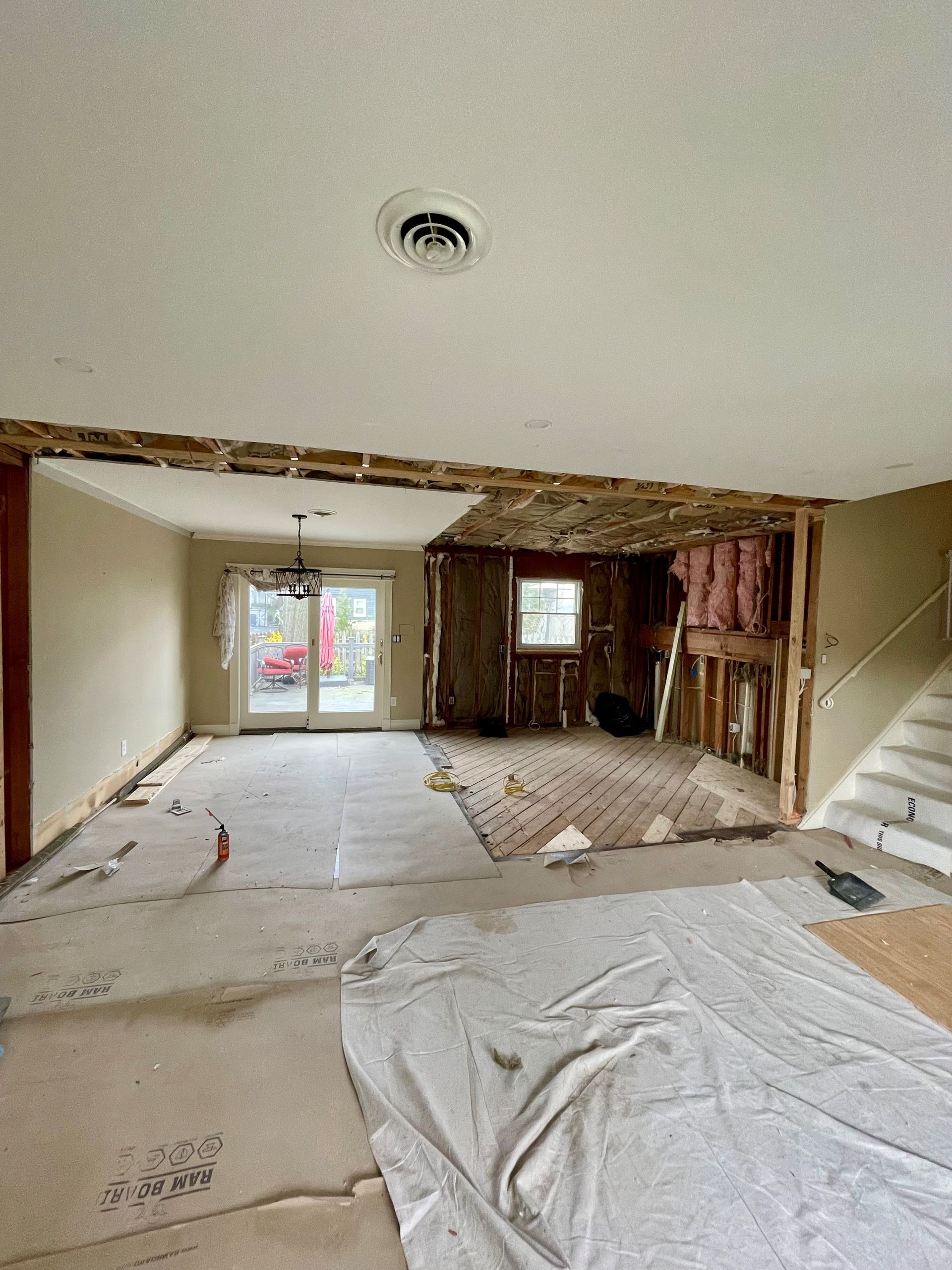 A large empty room with a ceiling fan and stairs.