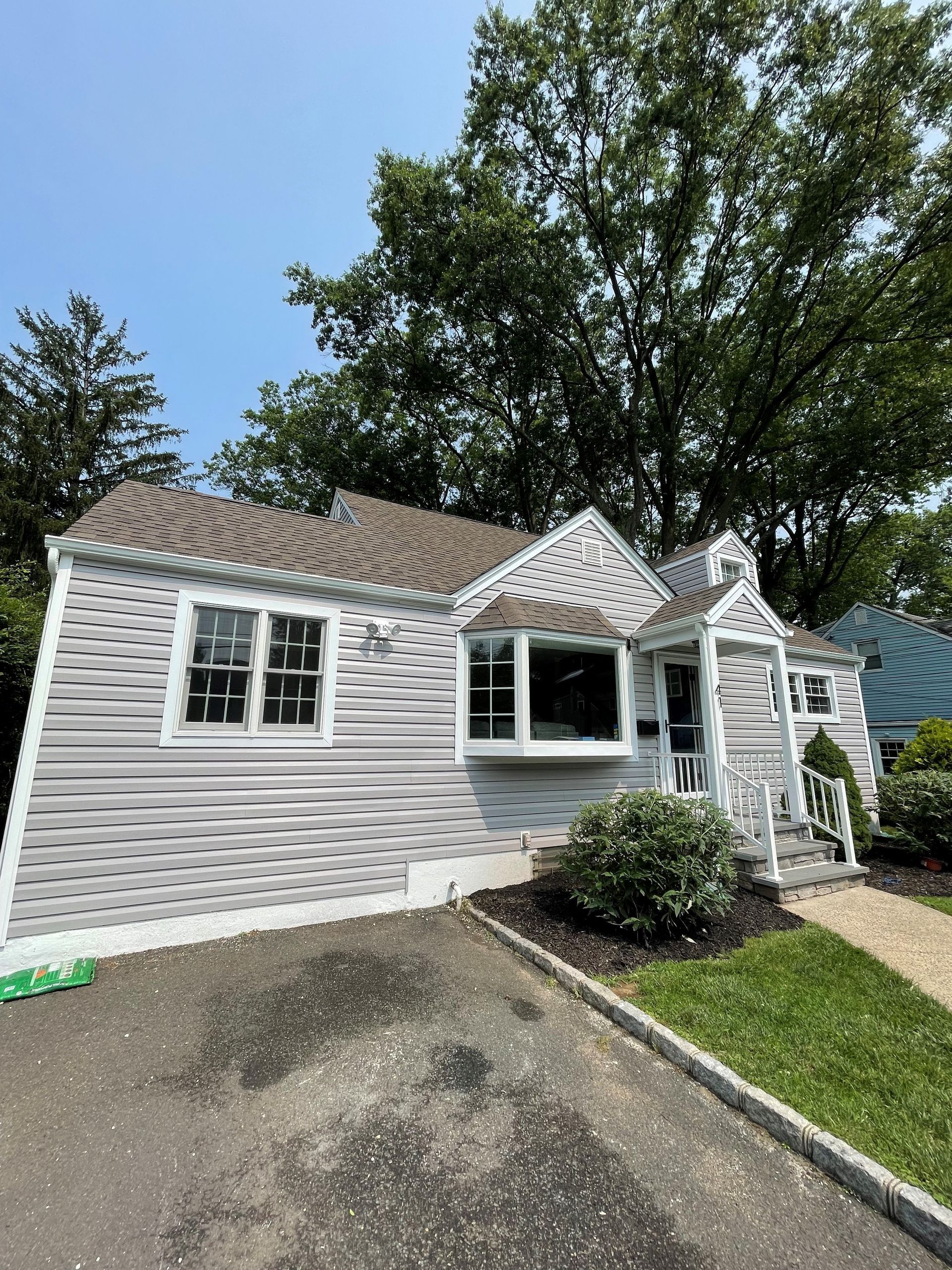 A white house with a brown roof is surrounded by trees.