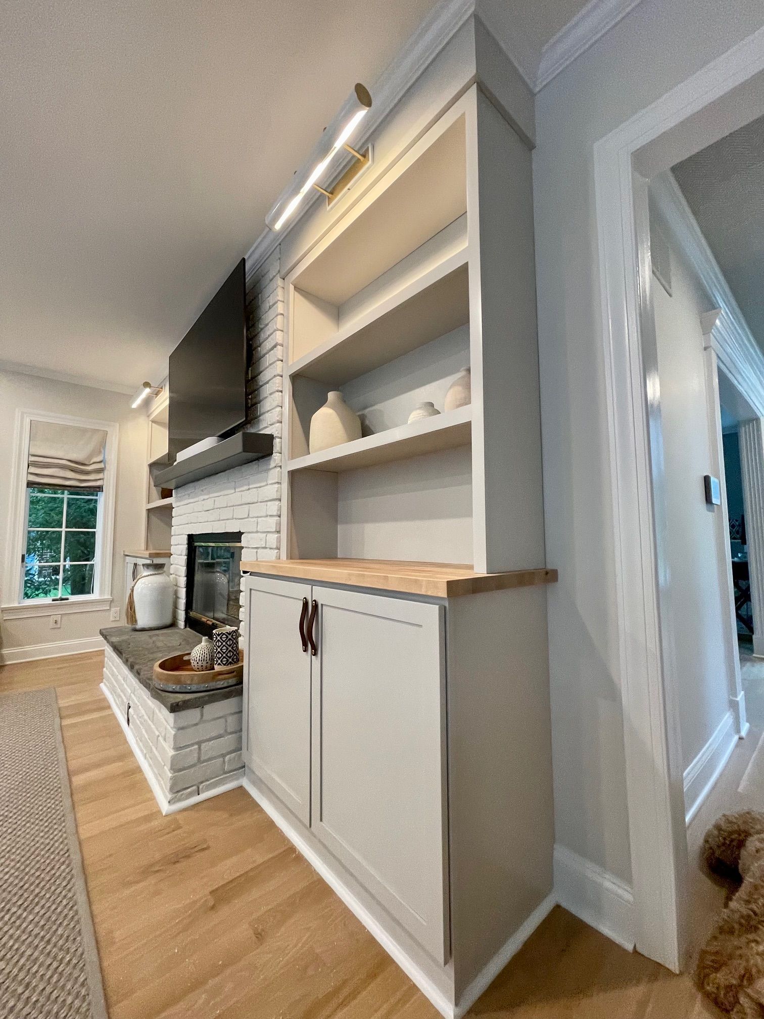 A living room with a fireplace, shelves, cabinets, and a television.