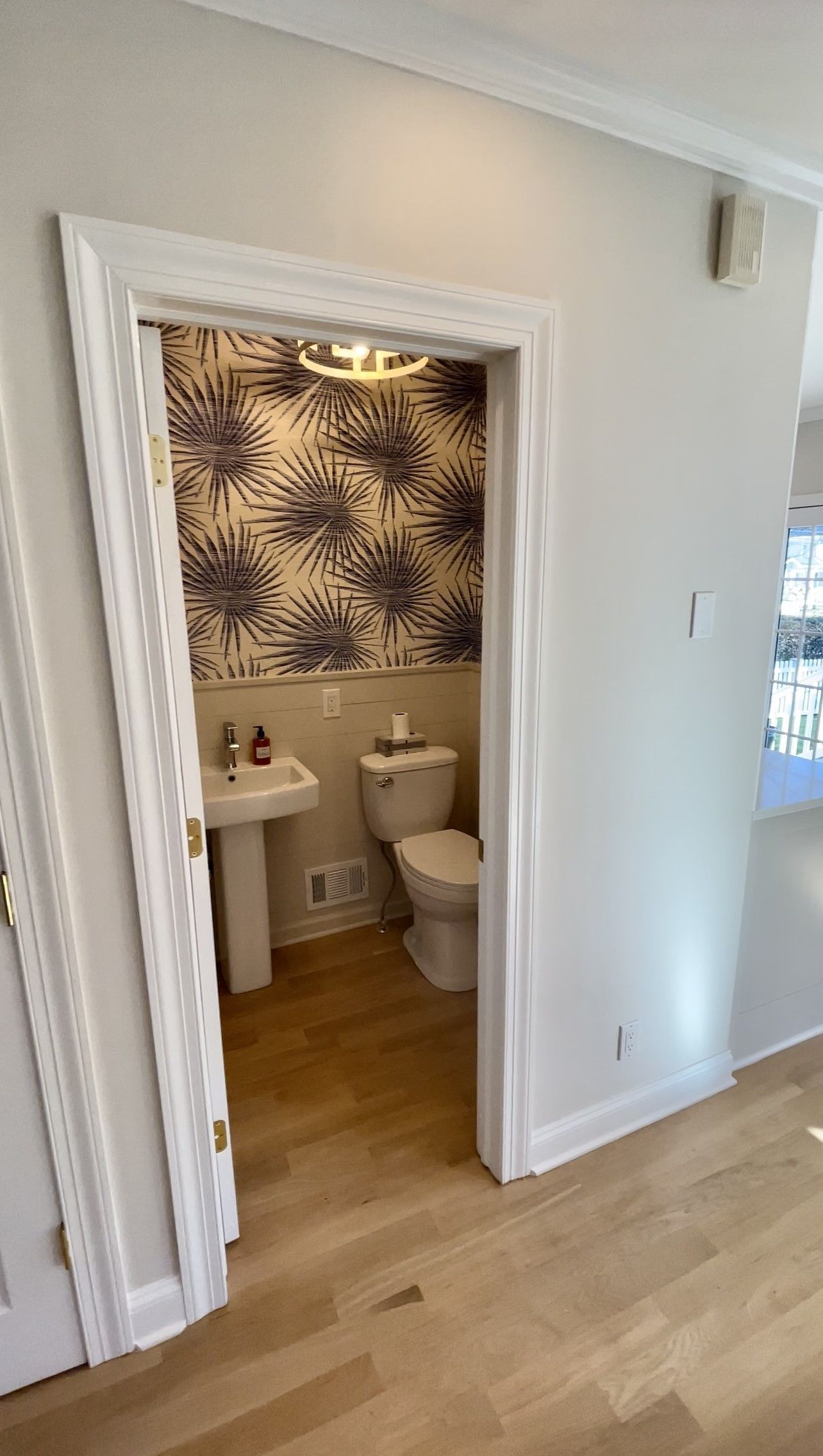 A bathroom with a sink, toilet, and wallpaper on the wall.
