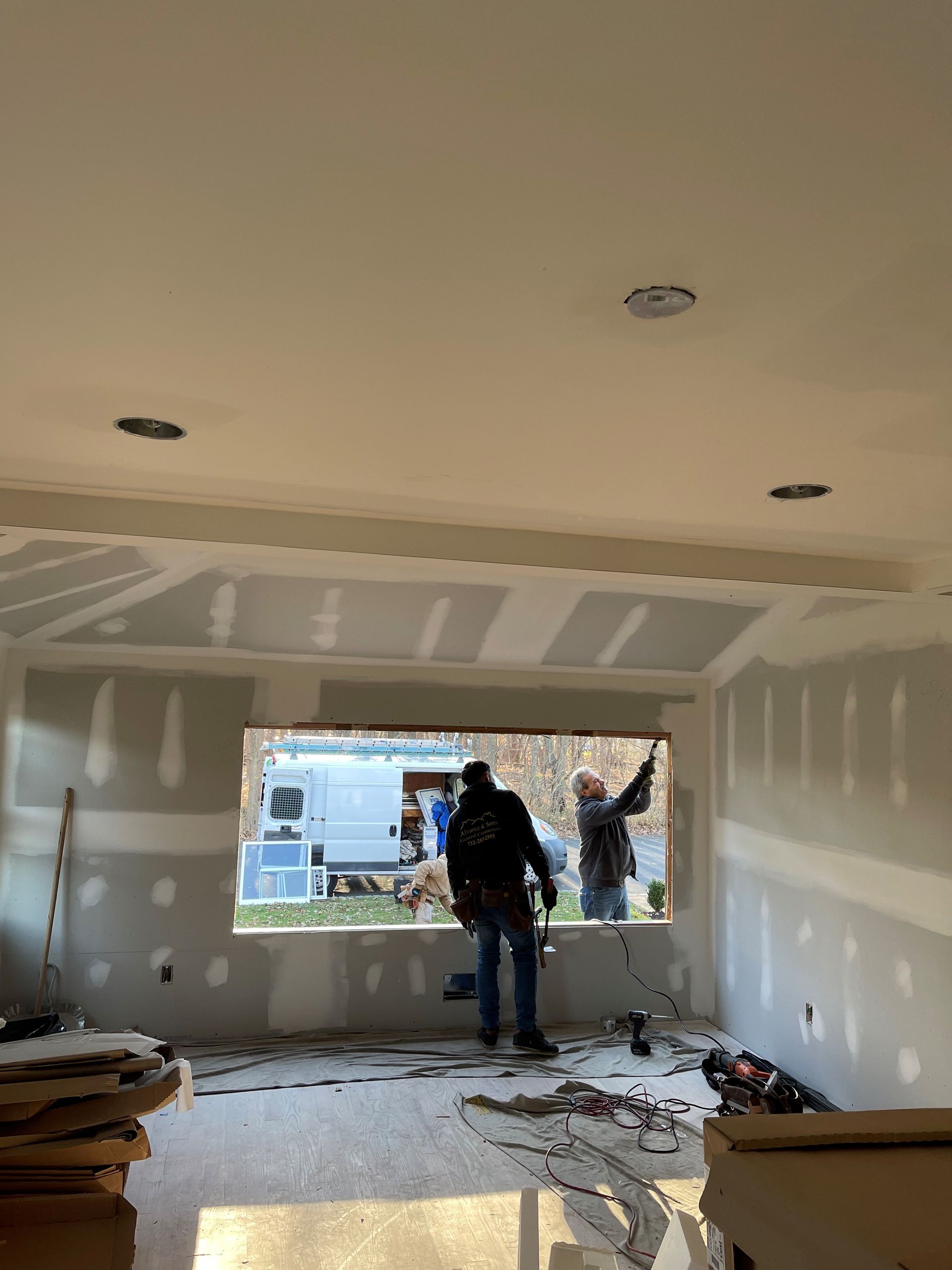 Two men are working on a window in a room