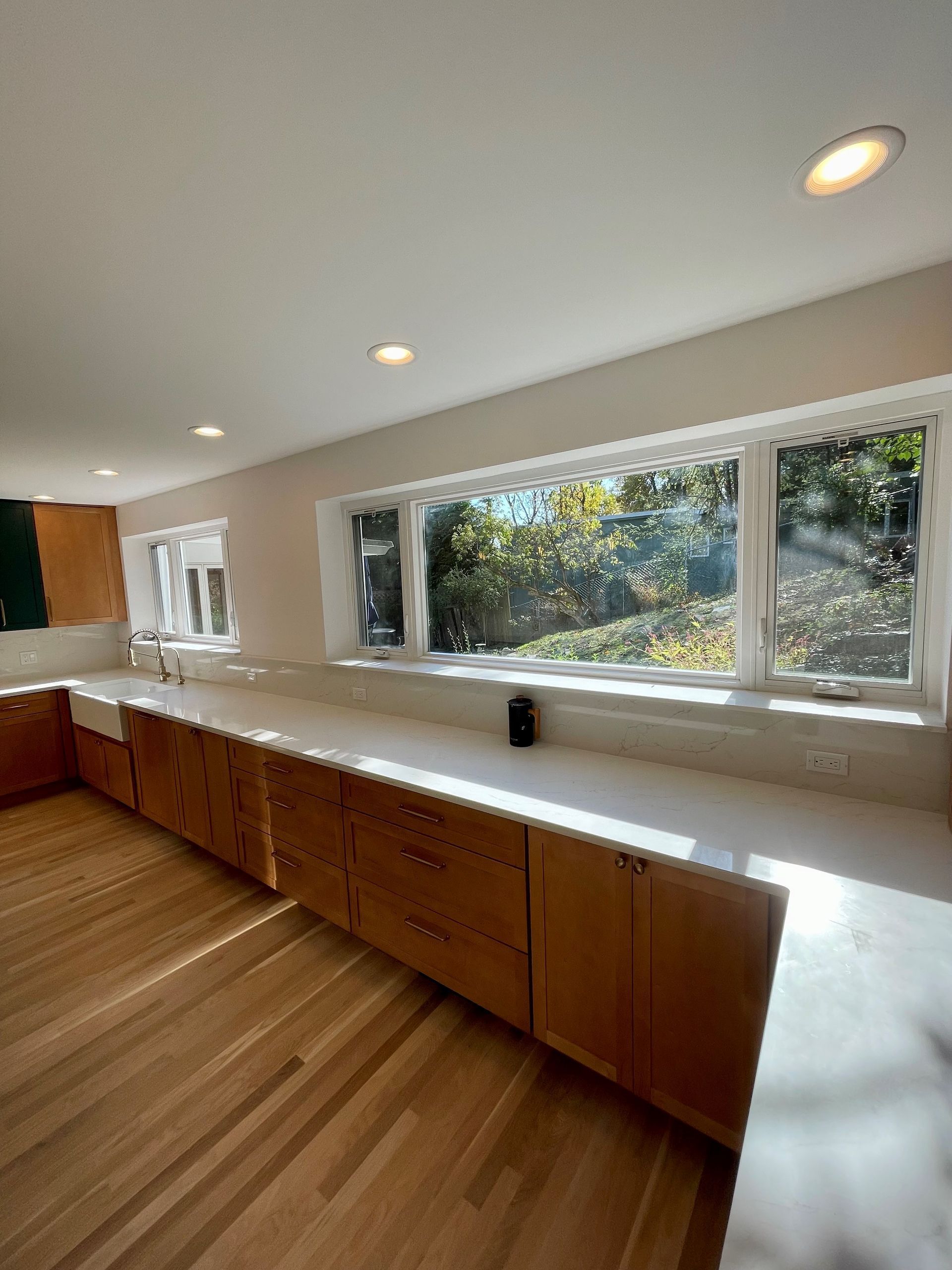A kitchen with a lot of windows and wooden cabinets