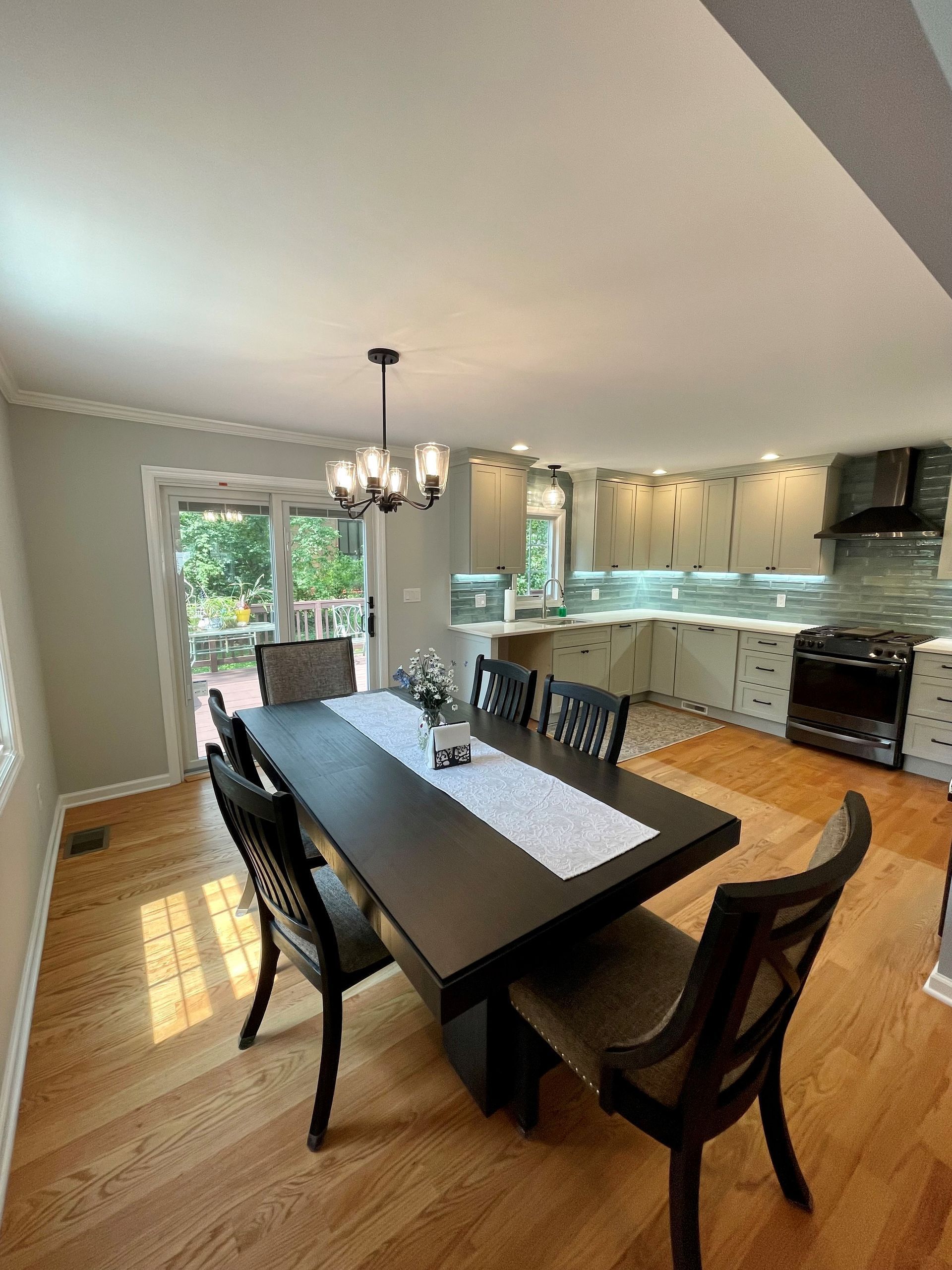 A dining room with a table and chairs and a kitchen in the background.