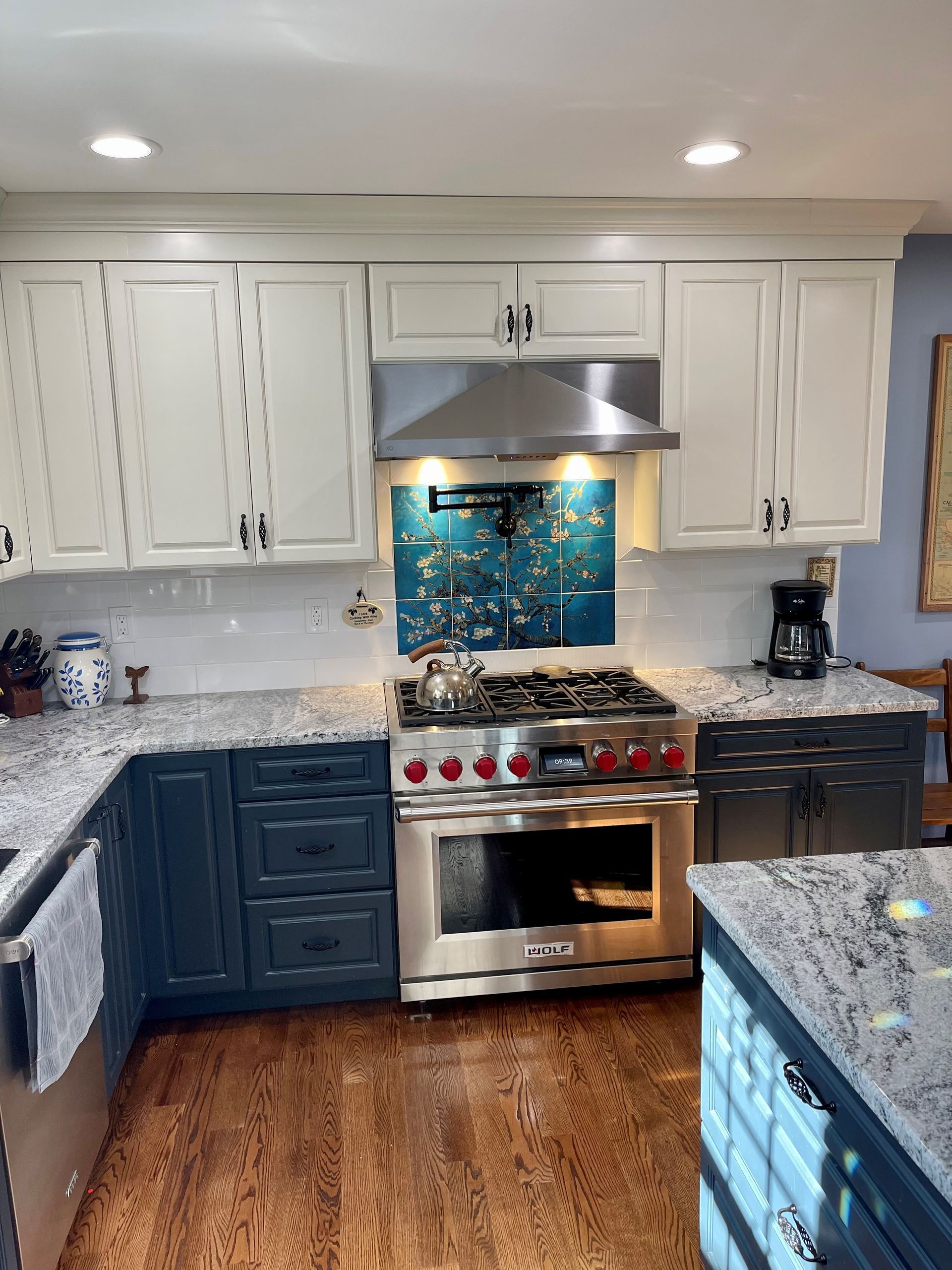 A kitchen with stainless steel appliances, granite counter tops, and blue cabinets.
