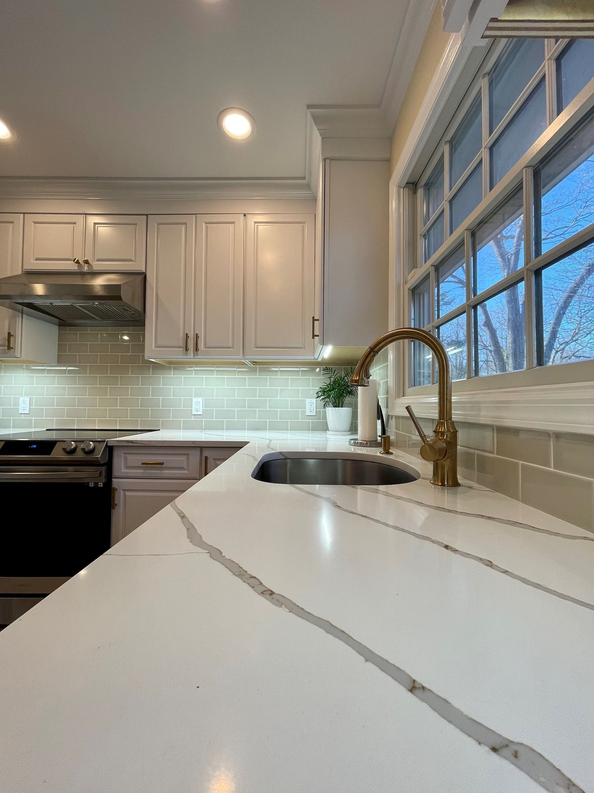 A kitchen with white cabinets and a sink and a window