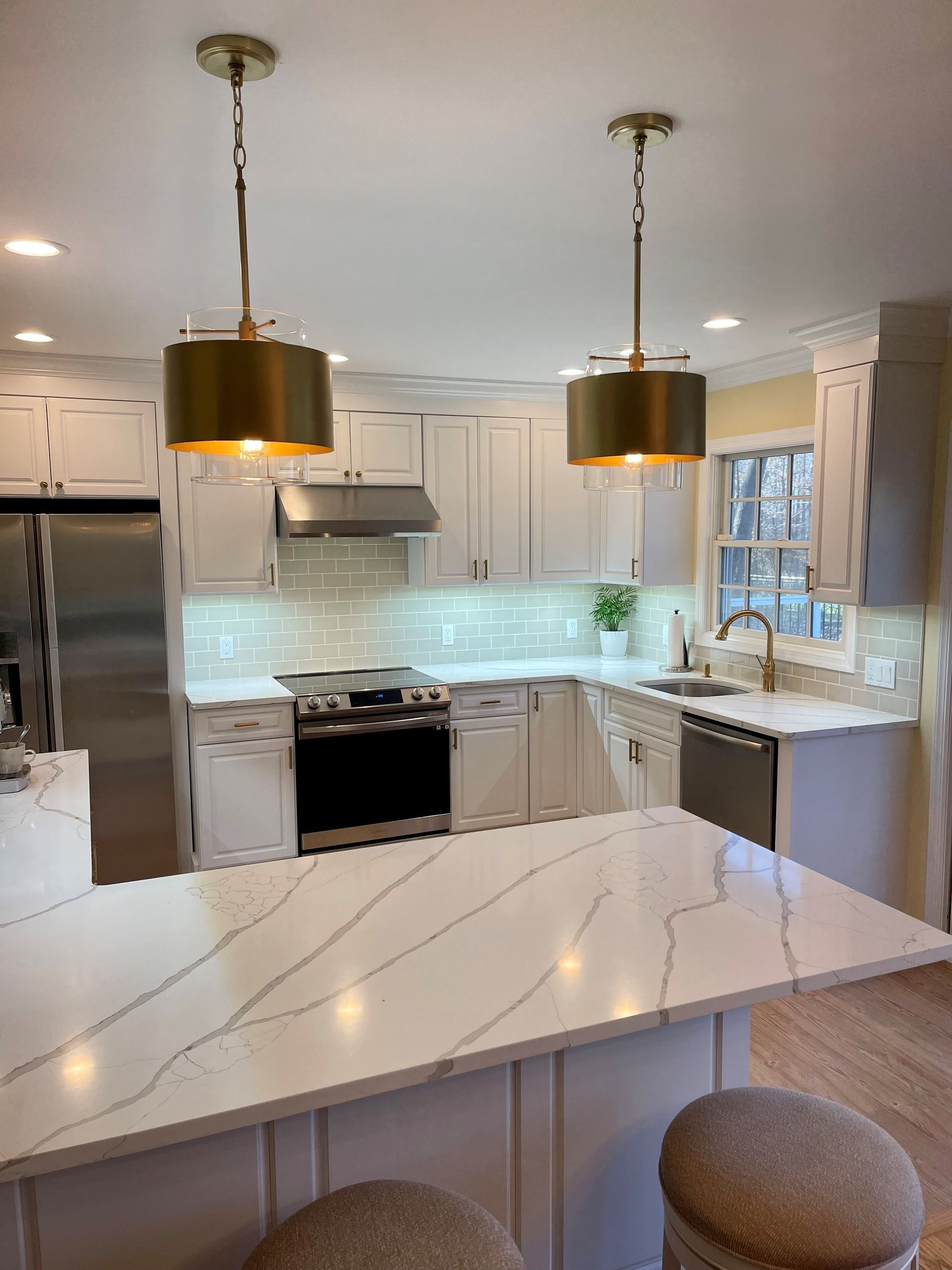 A kitchen with white cabinets, stainless steel appliances, and a large island.