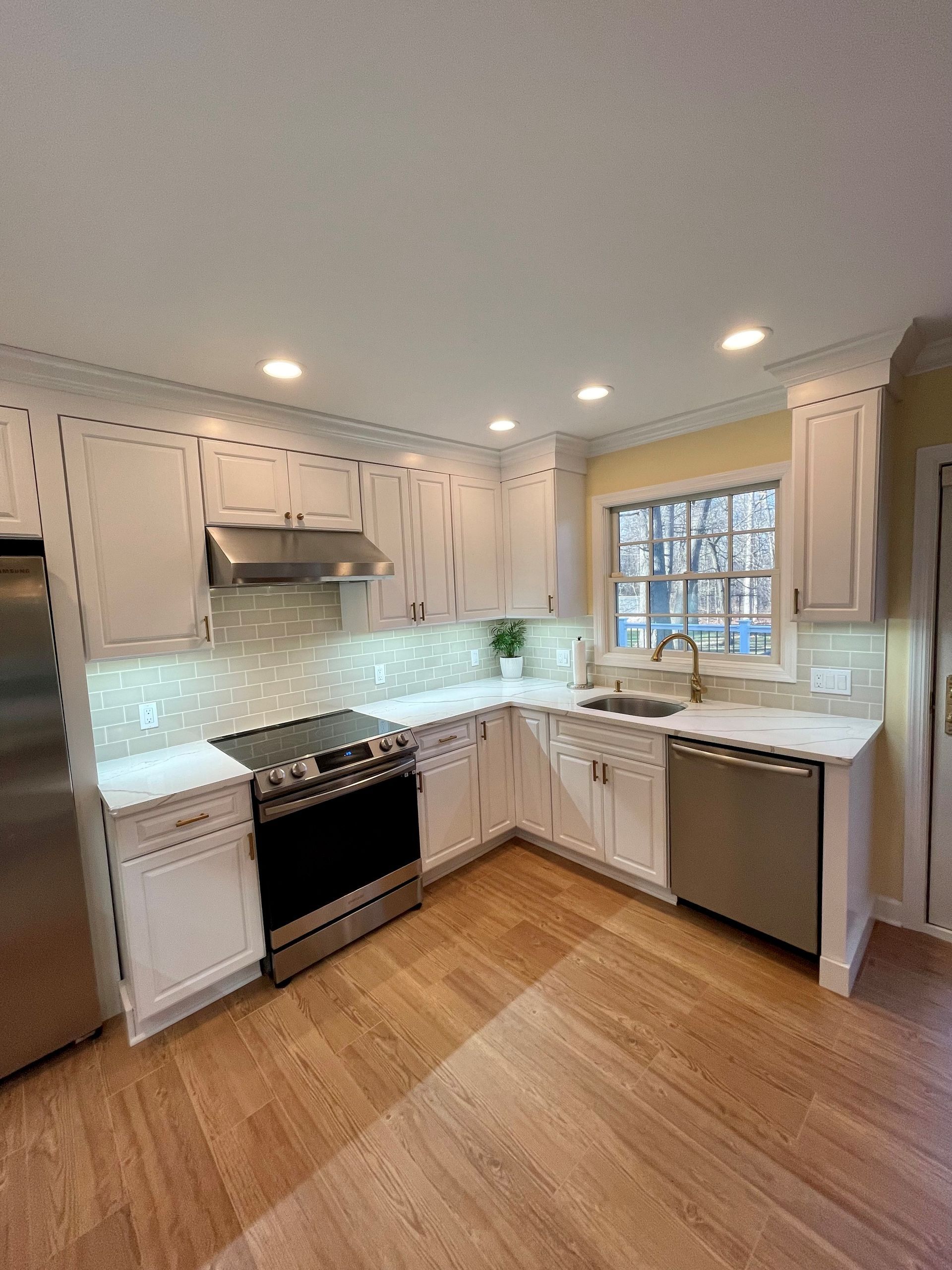 A kitchen with white cabinets, stainless steel appliances, a sink, and a stove.