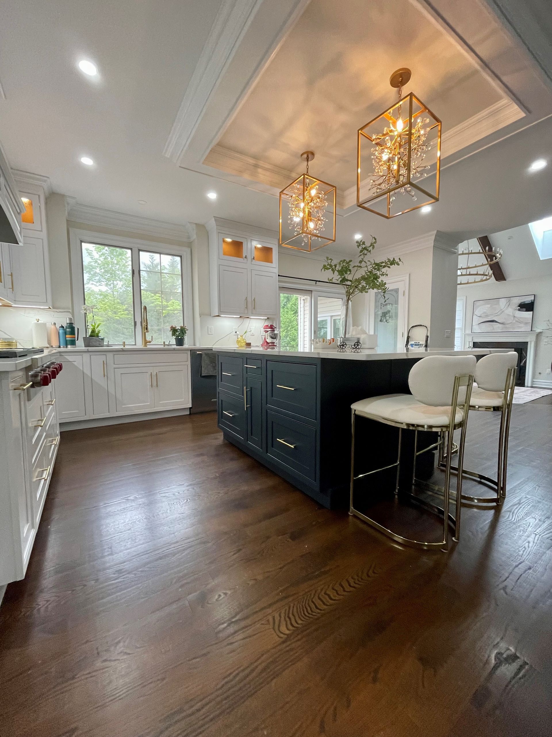 A kitchen with hardwood floors, white cabinets, and a large island.