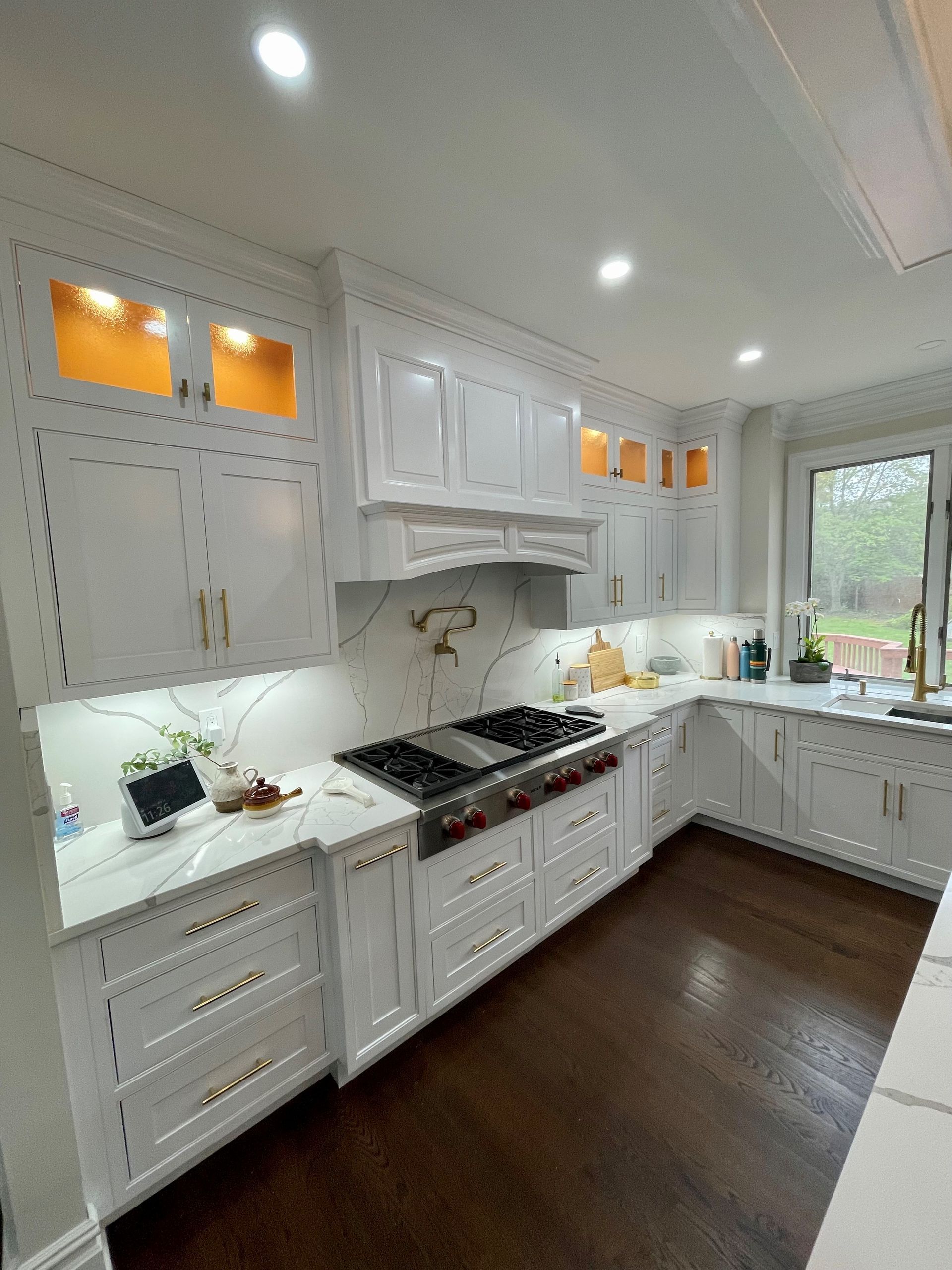 A kitchen with white cabinets, a stove, a sink, and a window.