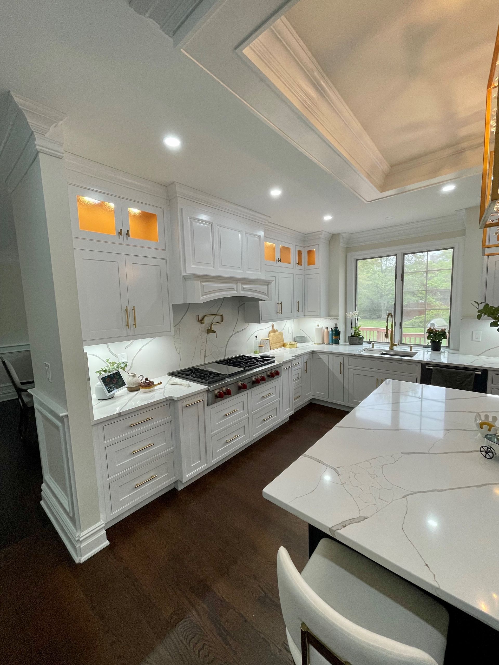 A kitchen with white cabinets, a stove, a sink, and a large island.