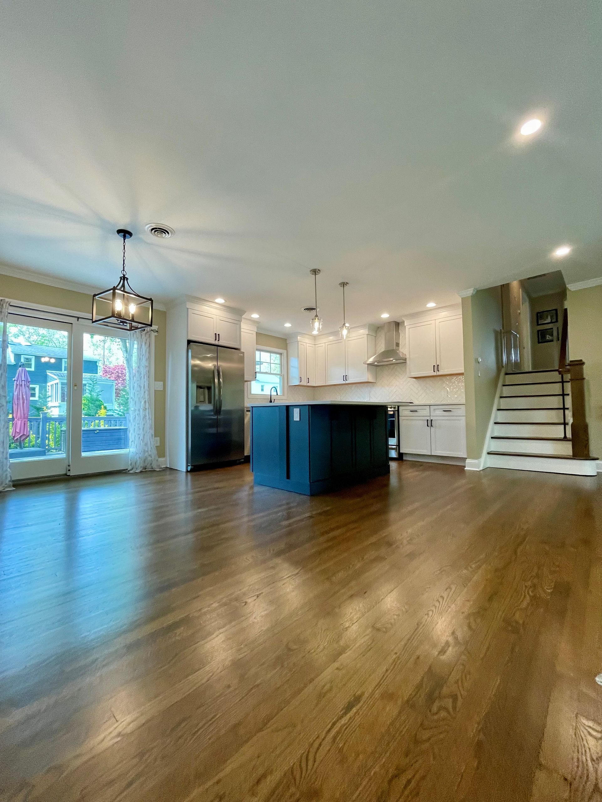 A large empty living room with hardwood floors and a kitchen.