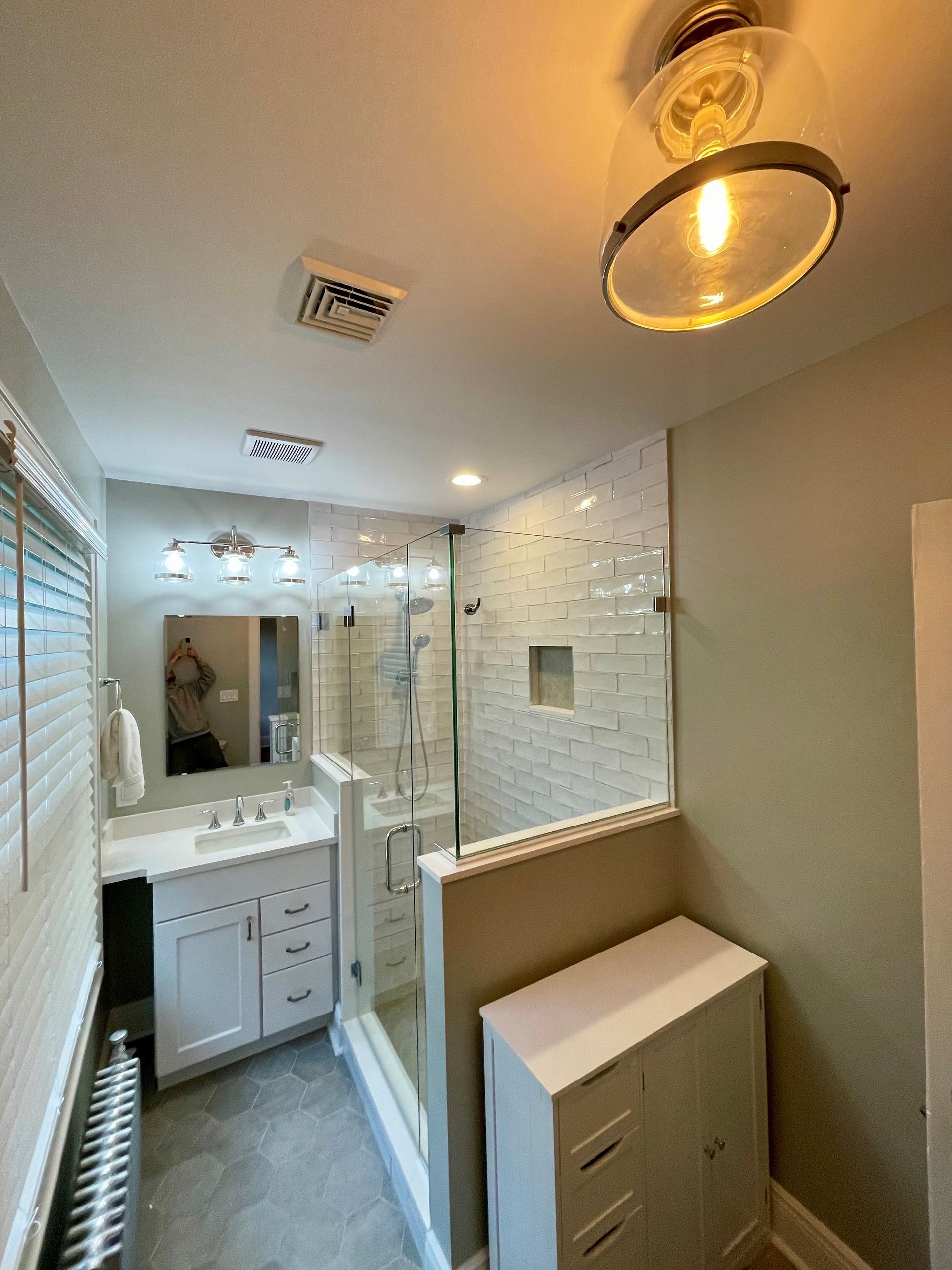 A bathroom with a sink, mirror, and shower.
