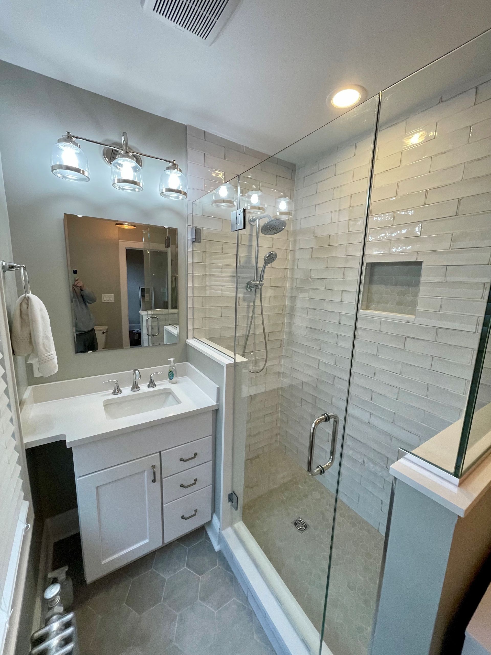 A bathroom with a sink and a shower with a glass door.