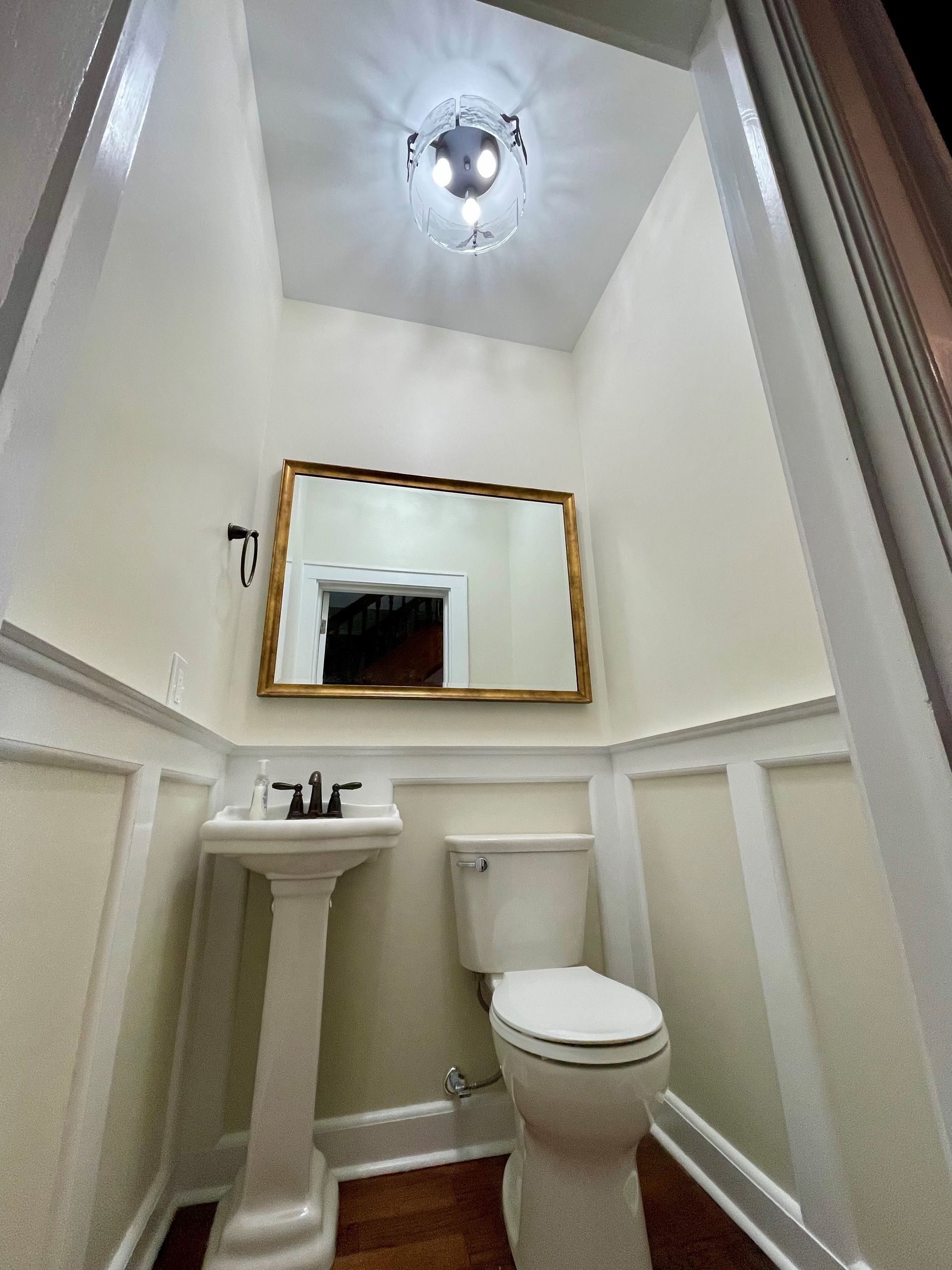 A bathroom with a toilet, sink and mirror.