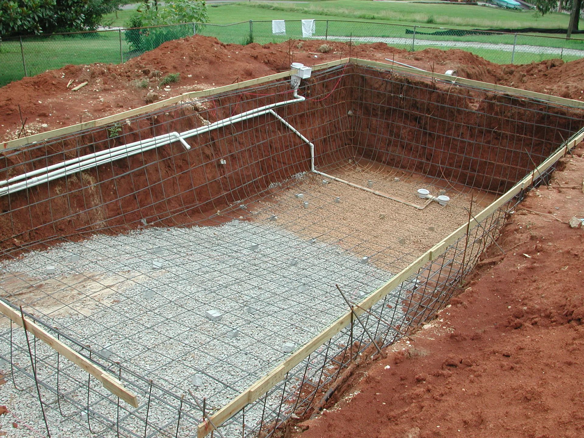 A large swimming pool is being built in the dirt.