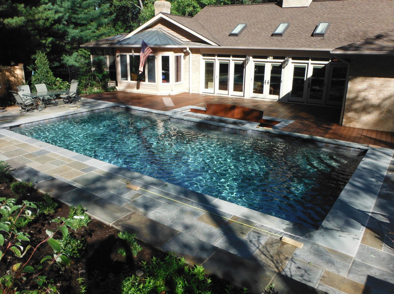 A house with a large swimming pool in front of it.