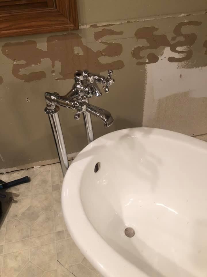 Vintage faucet above a white sink with water stains on the wall behind it
