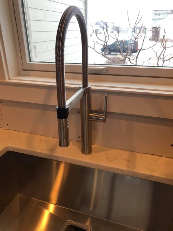 Kitchen sink with stainless steel faucet beneath a window above a metal basin