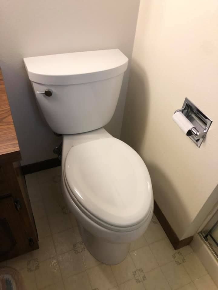 Small bathroom with a white toilet next to a wall-mounted toilet paper holder.