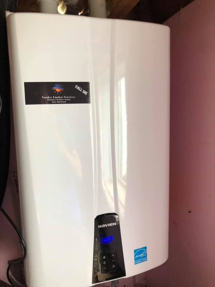 White wall-mounted water heater with a blue control panel in a pink-walled room