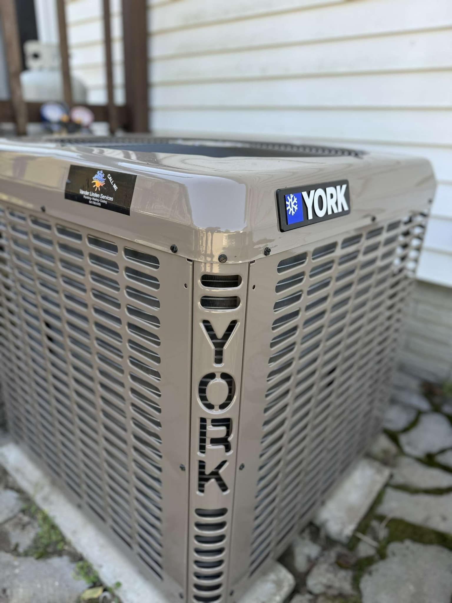 York outdoor air conditioner unit beside a house wall