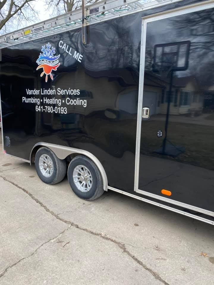 Black trailer for Vander Laan Services with logo and heating, cooling, plumbing text parked on a concrete driveway