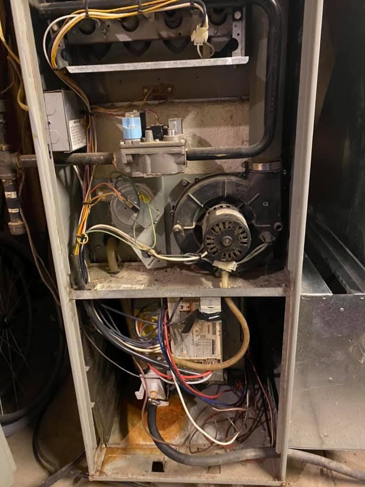 Open furnace or HVAC unit with exposed wiring, fan, and metal components inside a cabinet.
