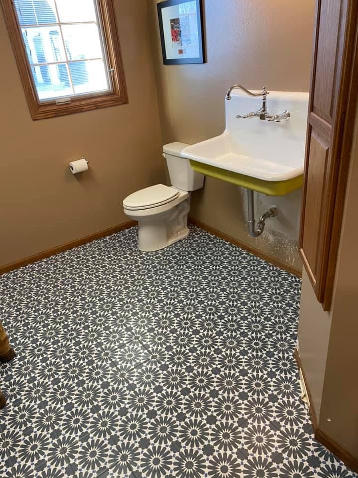 Accessible bathroom with toilet, wall sink, and patterned floor tiles.