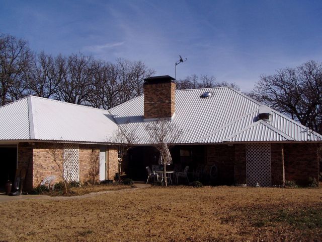 Single-story brick house with a white roof and chimney, seen from the front in winter.