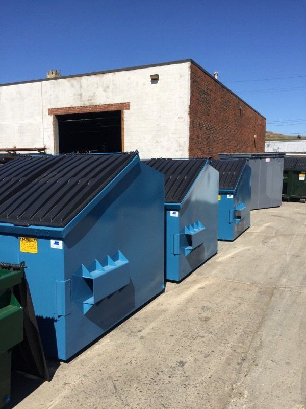 A row of dumpsters are lined up in front of a building